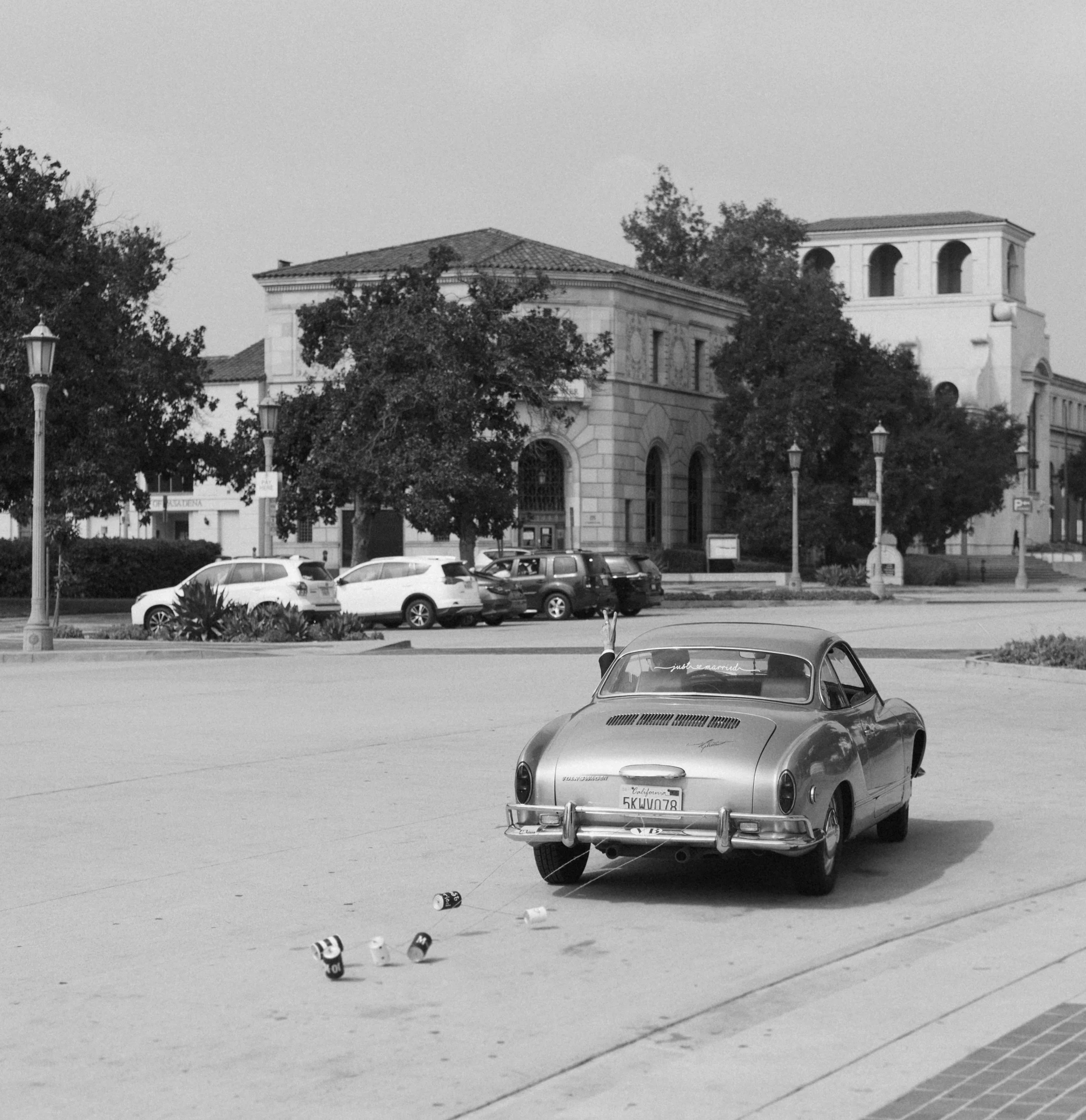 Vintage car with cans attached, parked near historic building