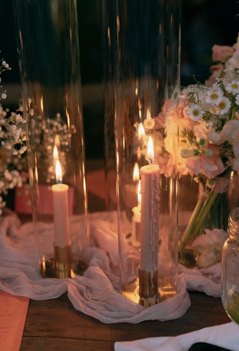 Candles in glass holders with flowers and fabric on a wooden table