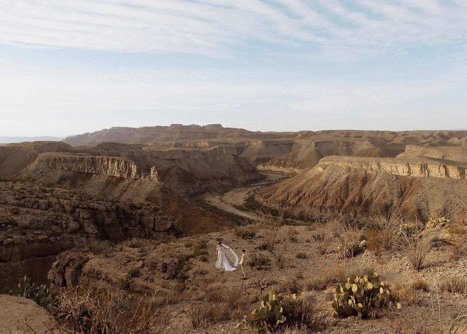 A couple stands atop a mesa with sweeping views and the Rio Grande in the background.