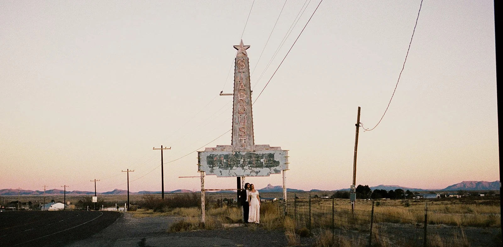A couple poses near the Stardust Motel sign on the edge of the town of Marfa.
