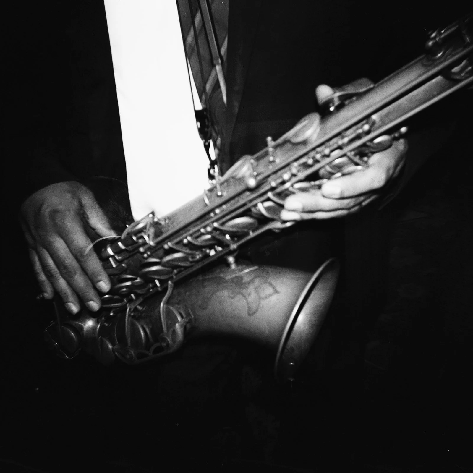 Close-up of a person playing an electric keyboard or digital piano, with their hands on the keys, in black and white.