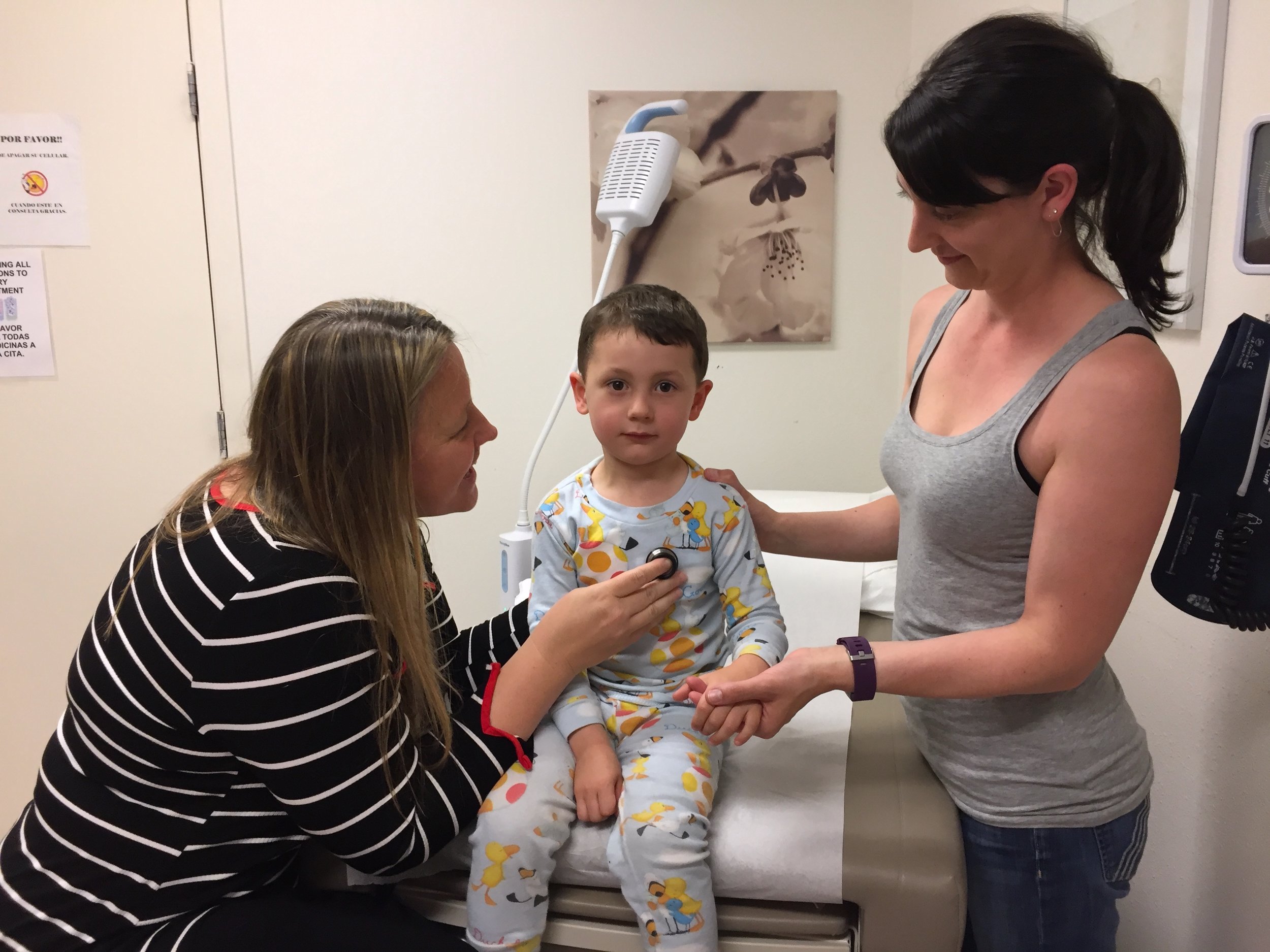 Corinda Hankins, MD, listens to the lungs of Porter Lorenzen while his mother, Jenny Lorenzen, holds his hand.