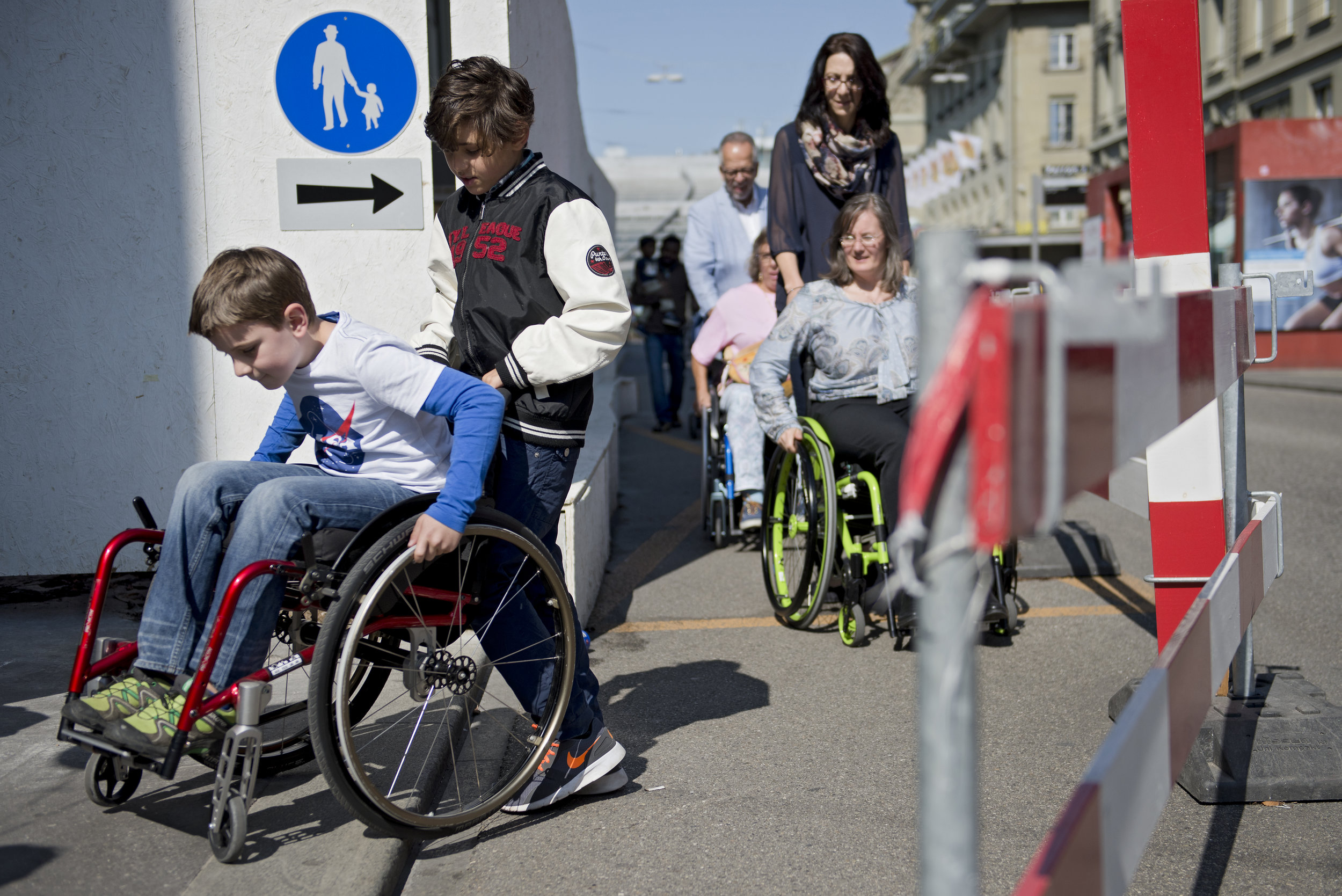 Auf einer Baustellen versucht ein Kind im Rollstuhl mühevoll den Absatz aufs Trottoir zu überwinden