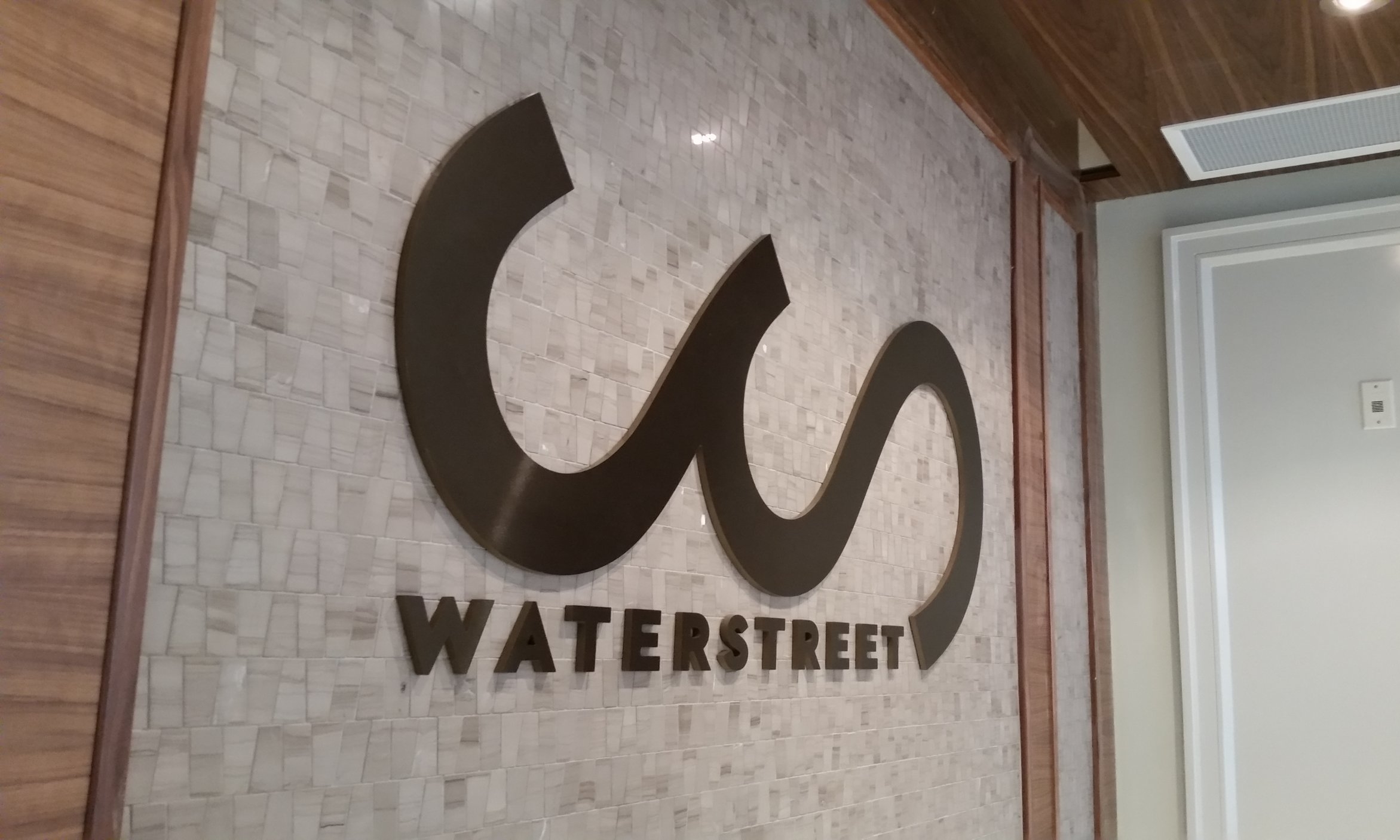 Brushed bronze laser cut logo, mounted to marble tile.