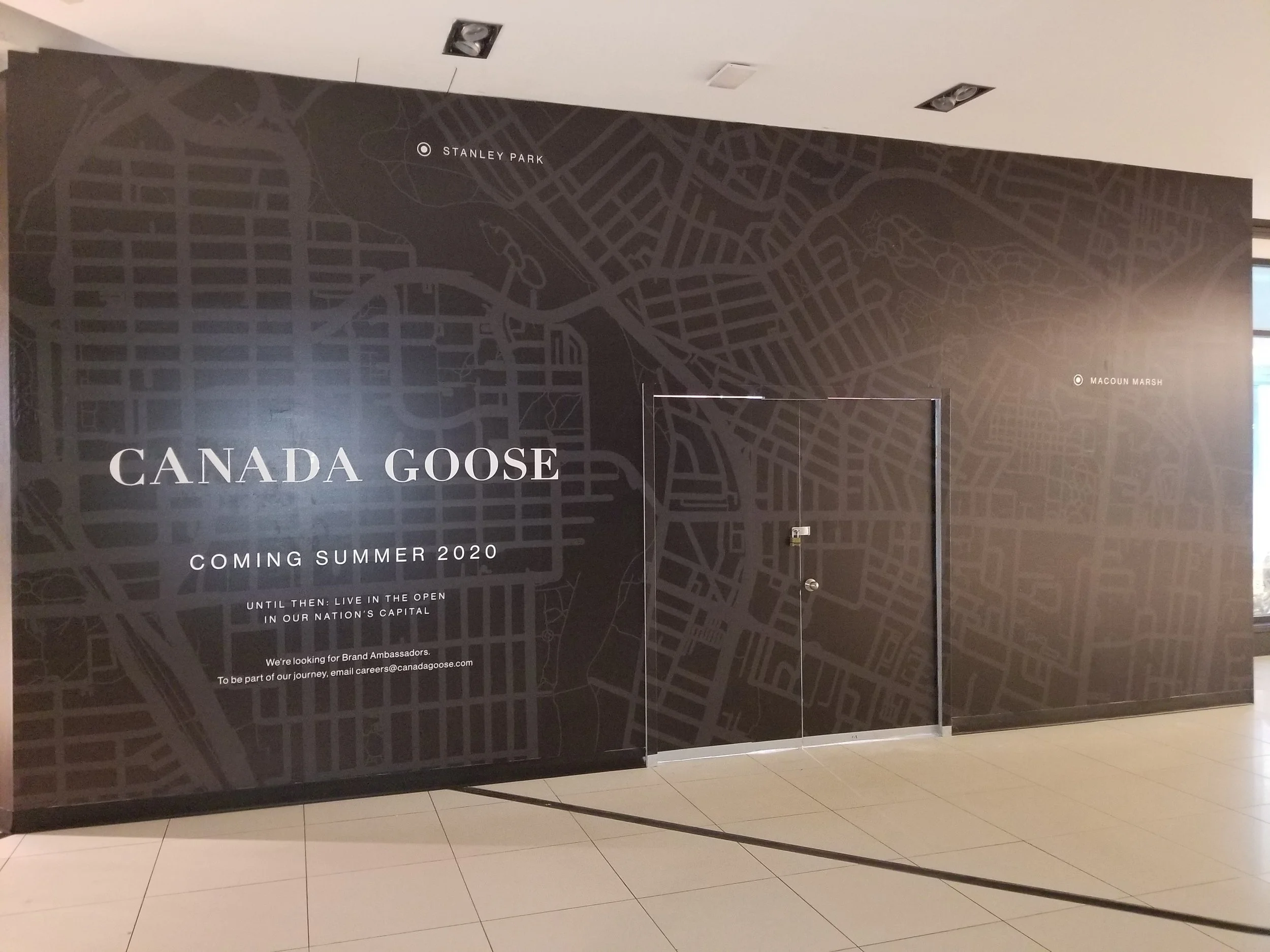 Black informational poster with a gray map of downtown Toronto, featuring notable locations such as Stanley Park and Macoun Marsh. The poster announces the Canada Goose brand's upcoming summer 2020 launch and encourages viewers to join their journey by becoming brand ambassadors, providing an email contact for careers.
