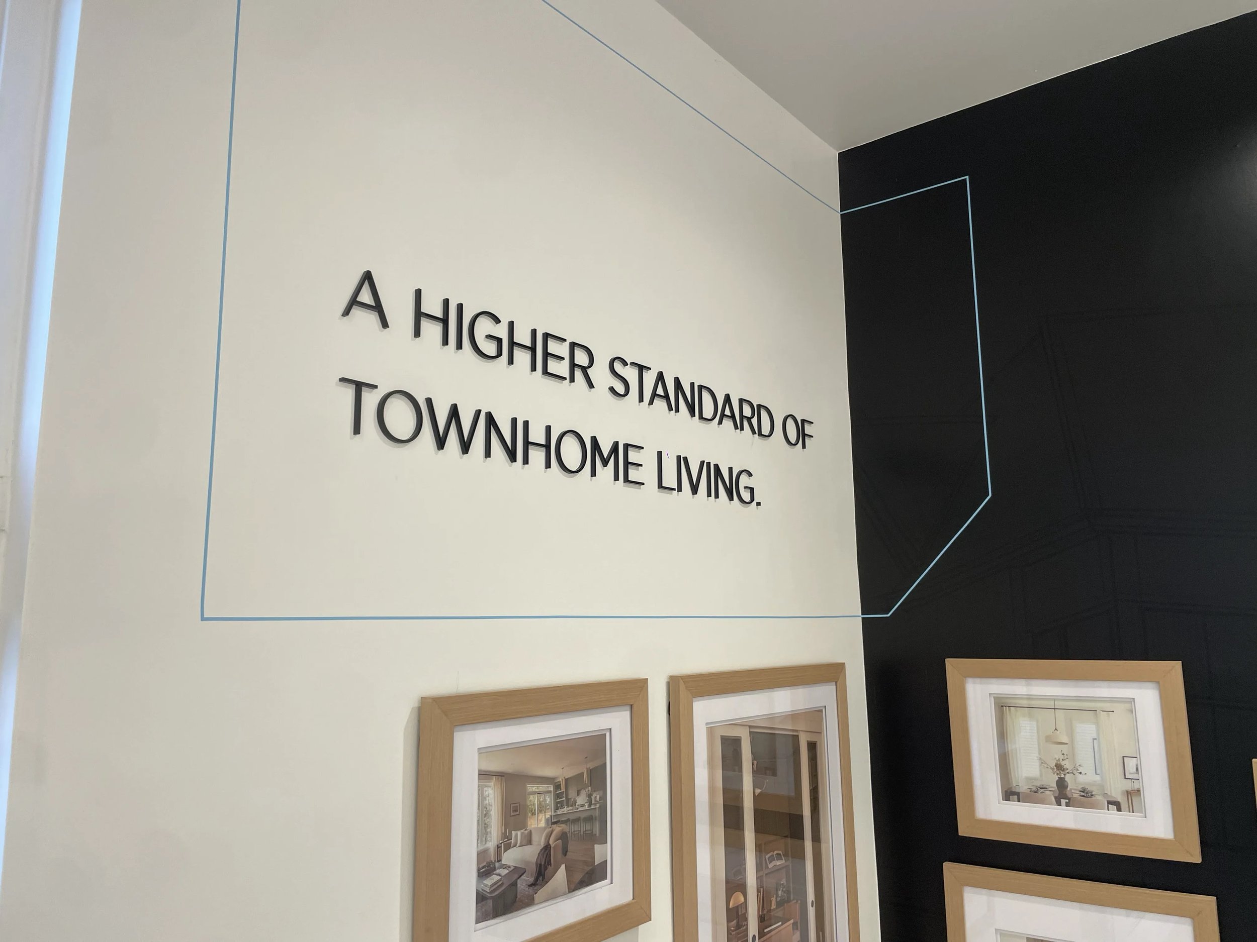 Interior wall display with framed pictures and a motivational quote, partially visible, about higher standards of townhouse living.