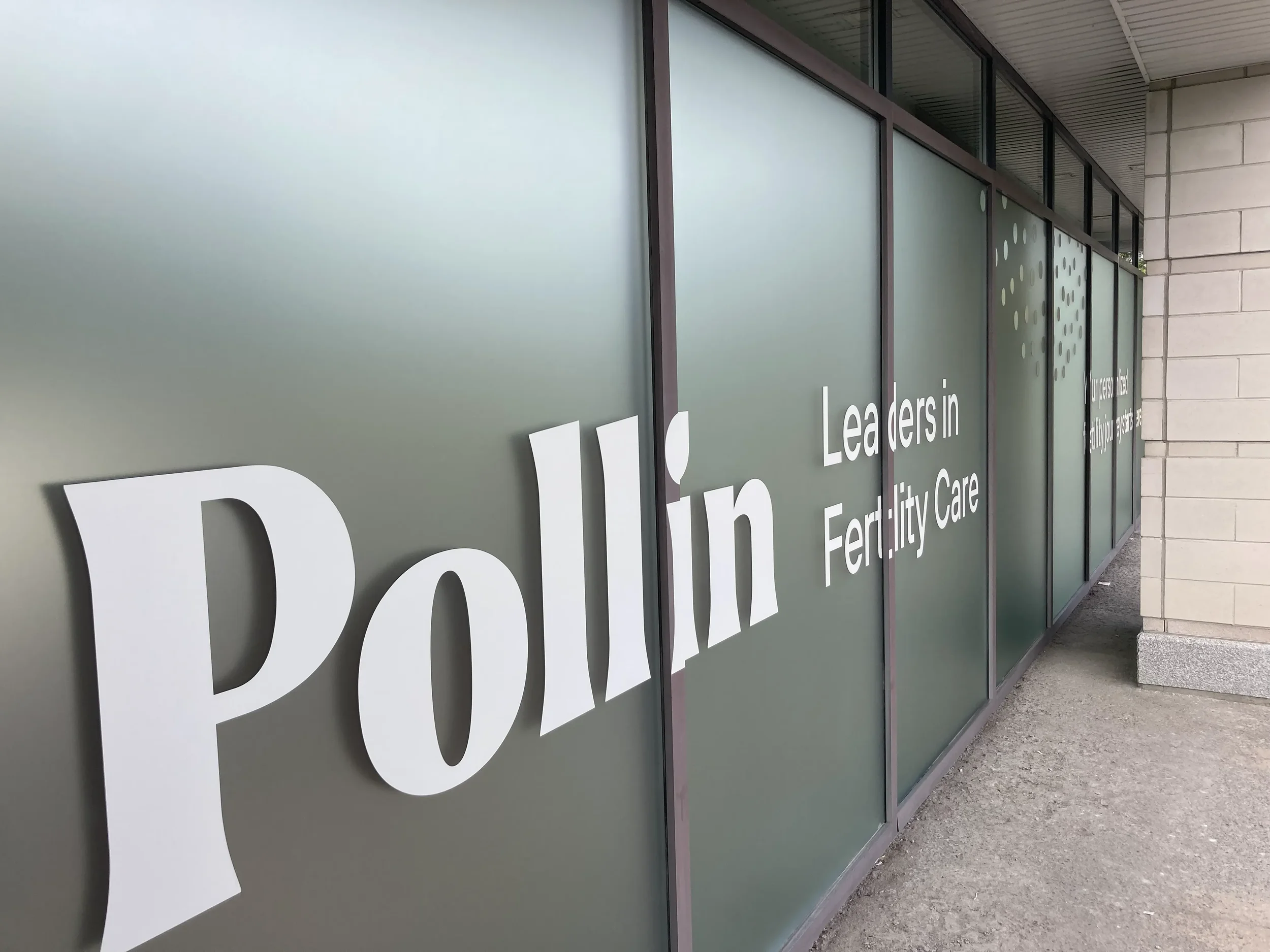Exterior view of a building with frosted glass windows decorated with white text and circular patterns, part of a sign that reads "Fertility Care".