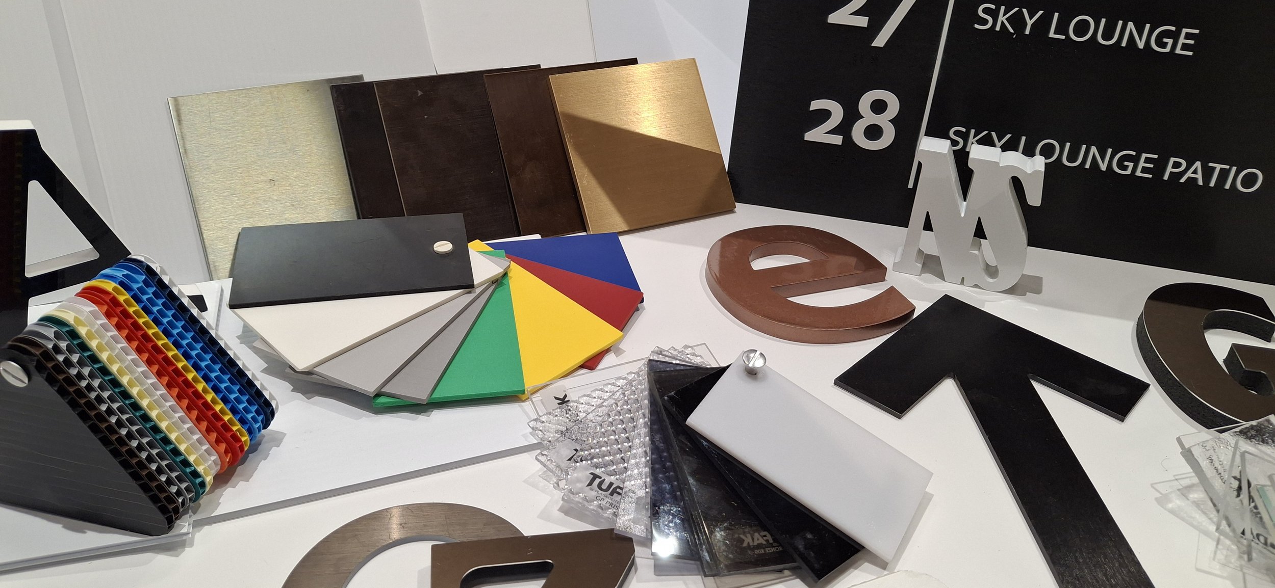 Interior design samples including color swatches, metallic and wood finish samples, decorative letters, and signage materials.