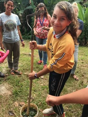 Estudiante de la escuela de nuestra comunidad preparando un bio-fermento de consuelda para nutrir las plantas del huerto escolar.