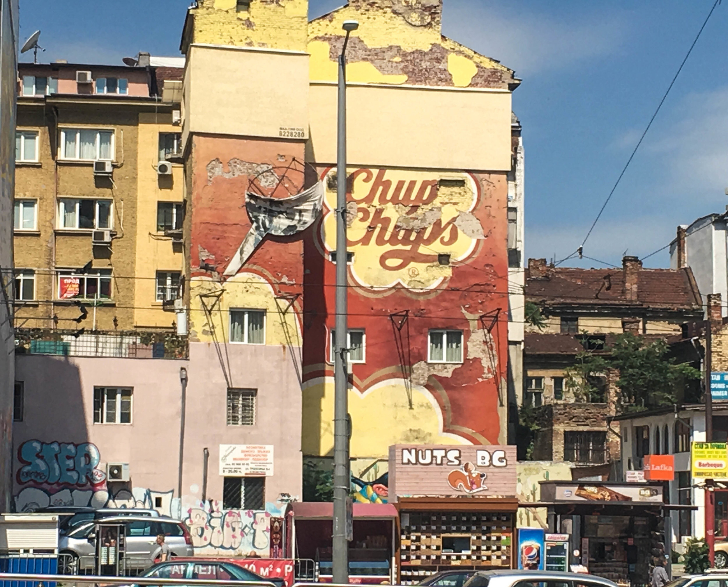 Sofia itinerary, Building in Sofia (Bulgaria) with a Chup Chups decaying mural and a nut stand. 