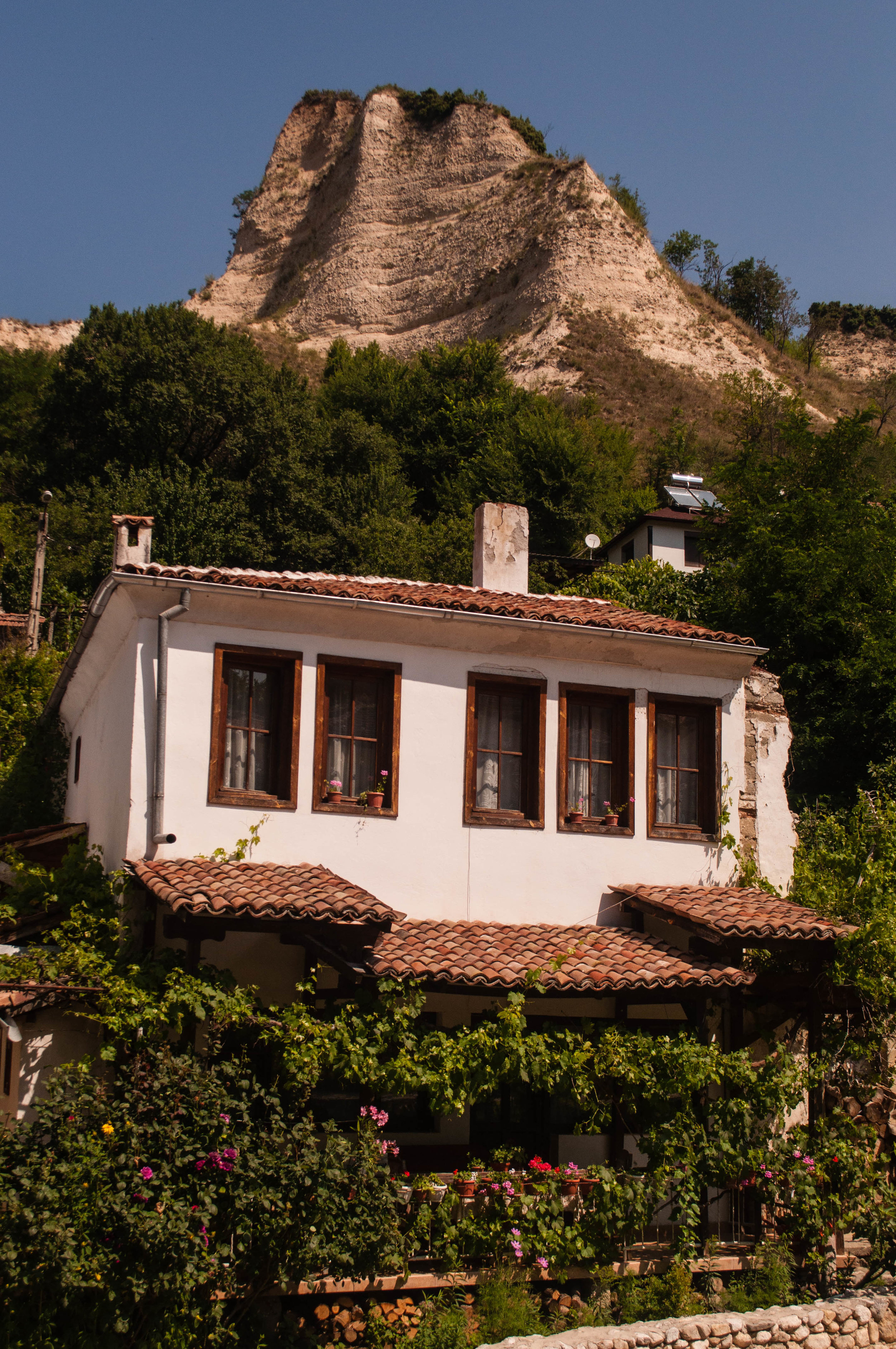Melnik traditional white house with the rock pyramids on the background.  This is a stop in our road trip Bulgaria