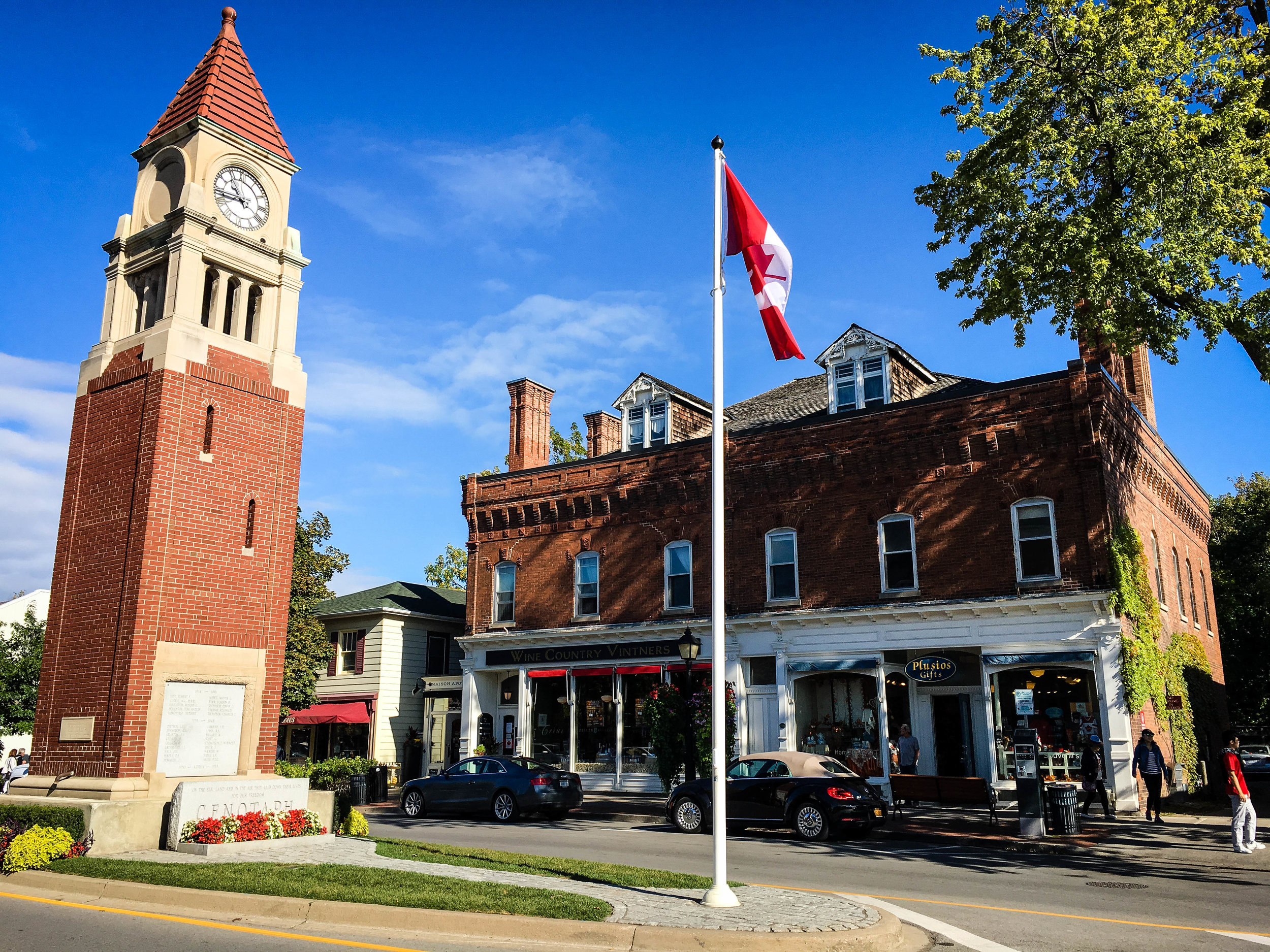 Niagara on the Lake town with a clock tower, the canadian flag and a victorian building 