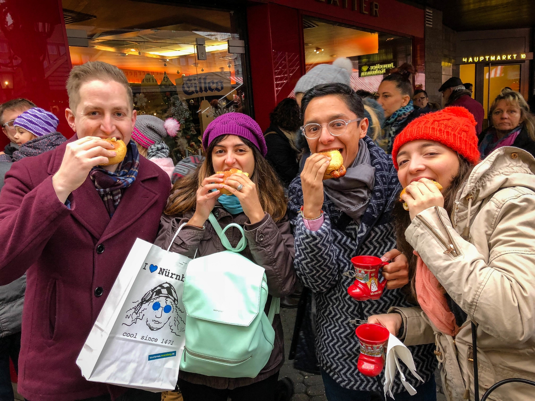 Images of a group of latinos in theNuremberg Christmas market eating Nuremberg grilled Sausages 