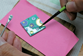 On the pendant, spread grains, working them against the cloisonné 