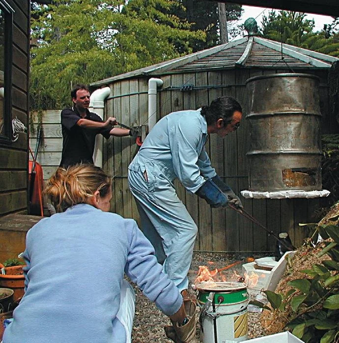 Author Stephen Wealthall with family help (and welding gloves) extracts hot glazed work for raku ﬁnishing.