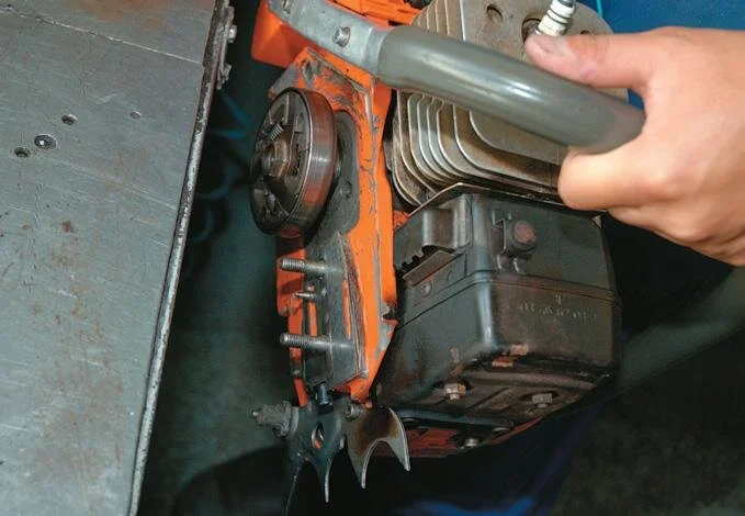 Method of checking the oil pump. Hold the machine close to the bench in case the sprocket ﬂies off