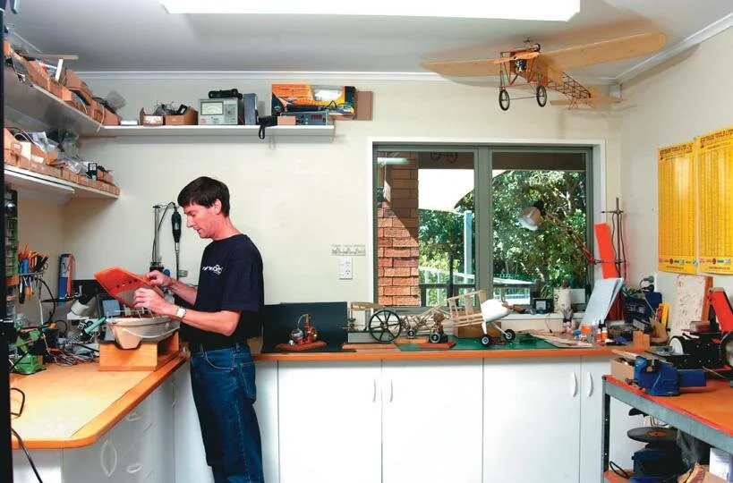Ross Purdy with model engines and boat in his shed