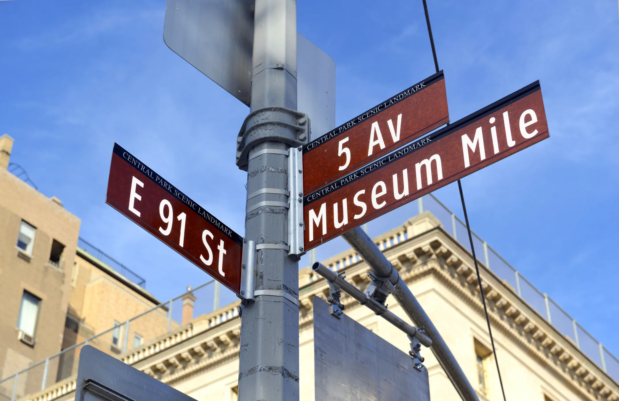 Street signs at East 91st Street and Fifth Avenue near Museum Mile in New York City, representing urban family life and metropolitan services.