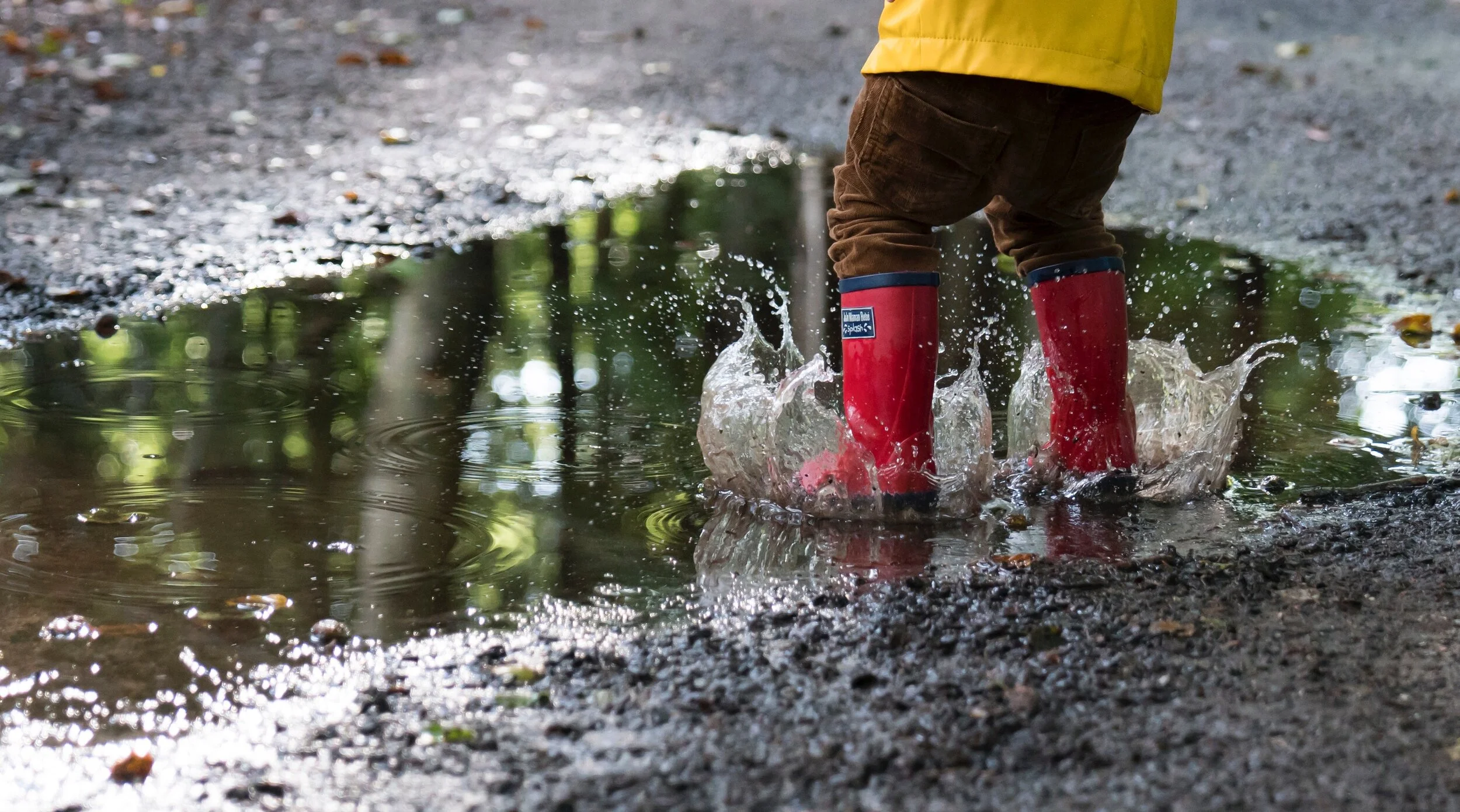 Children wearing rain boots standing together outdoors, representing rainy day activities with nanny kids.