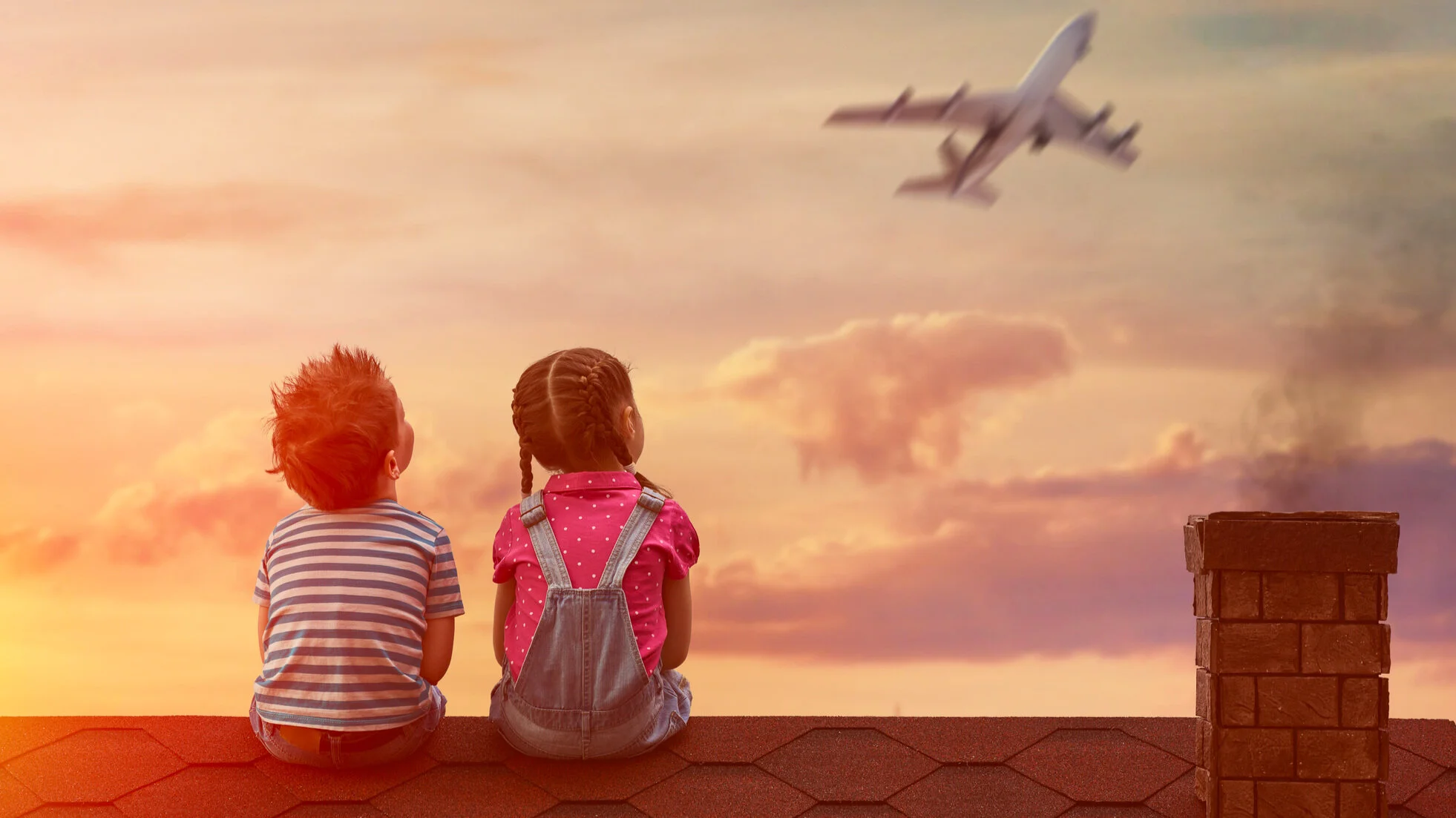 Two children sitting together watching an airplane fly overhead at sunset, symbolizing curiosity, growth, and global experiences