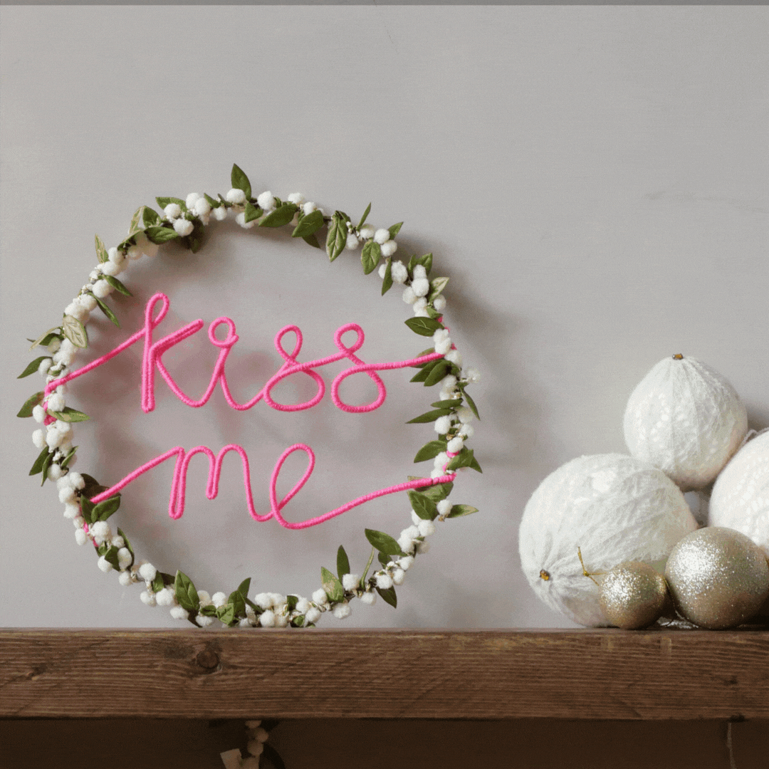 Illuminated Kiss Me mistletoe Christmas wreath styled on a mantel