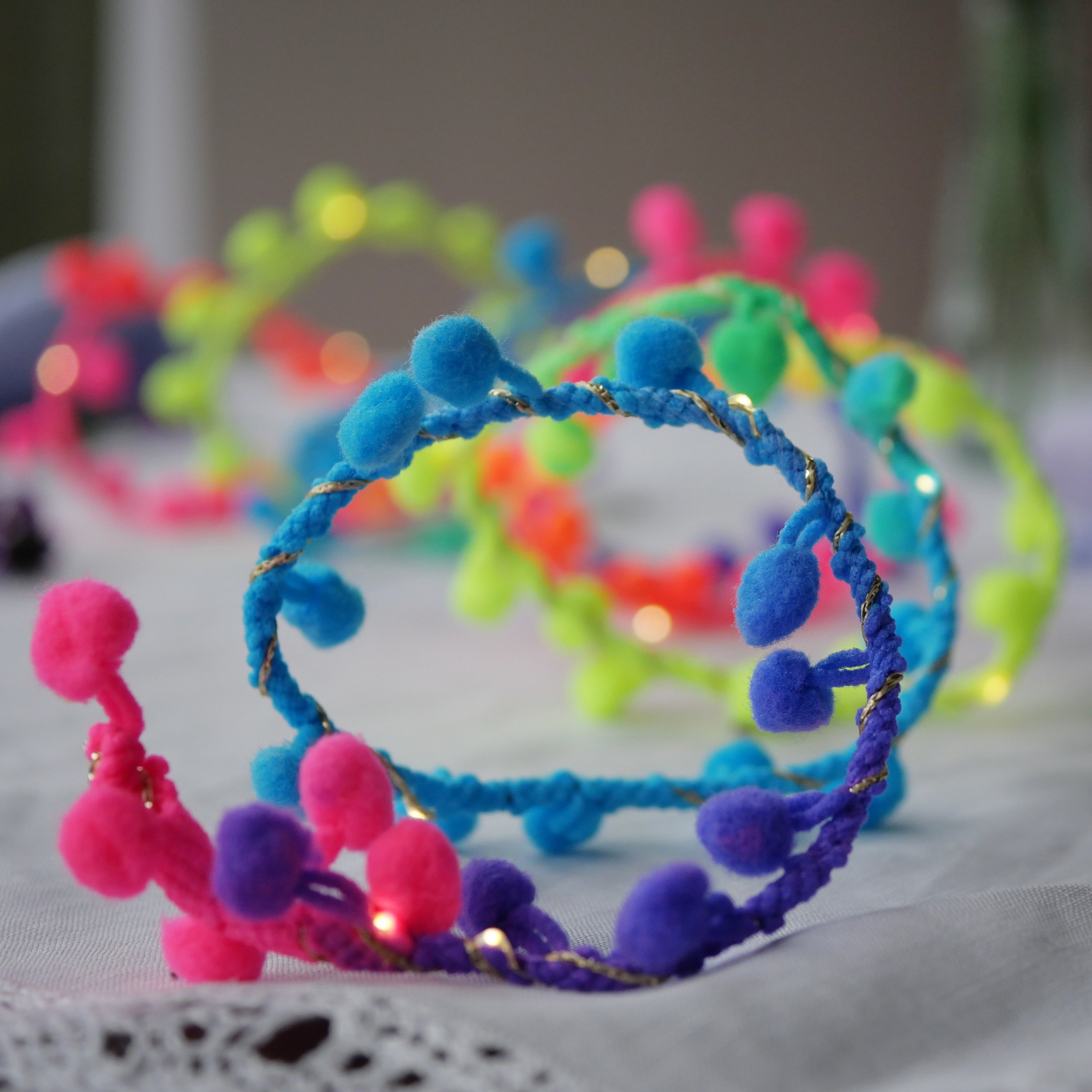 Colourful neon rainbow pom pom fairy lights with pink, blue, green and purple pom poms