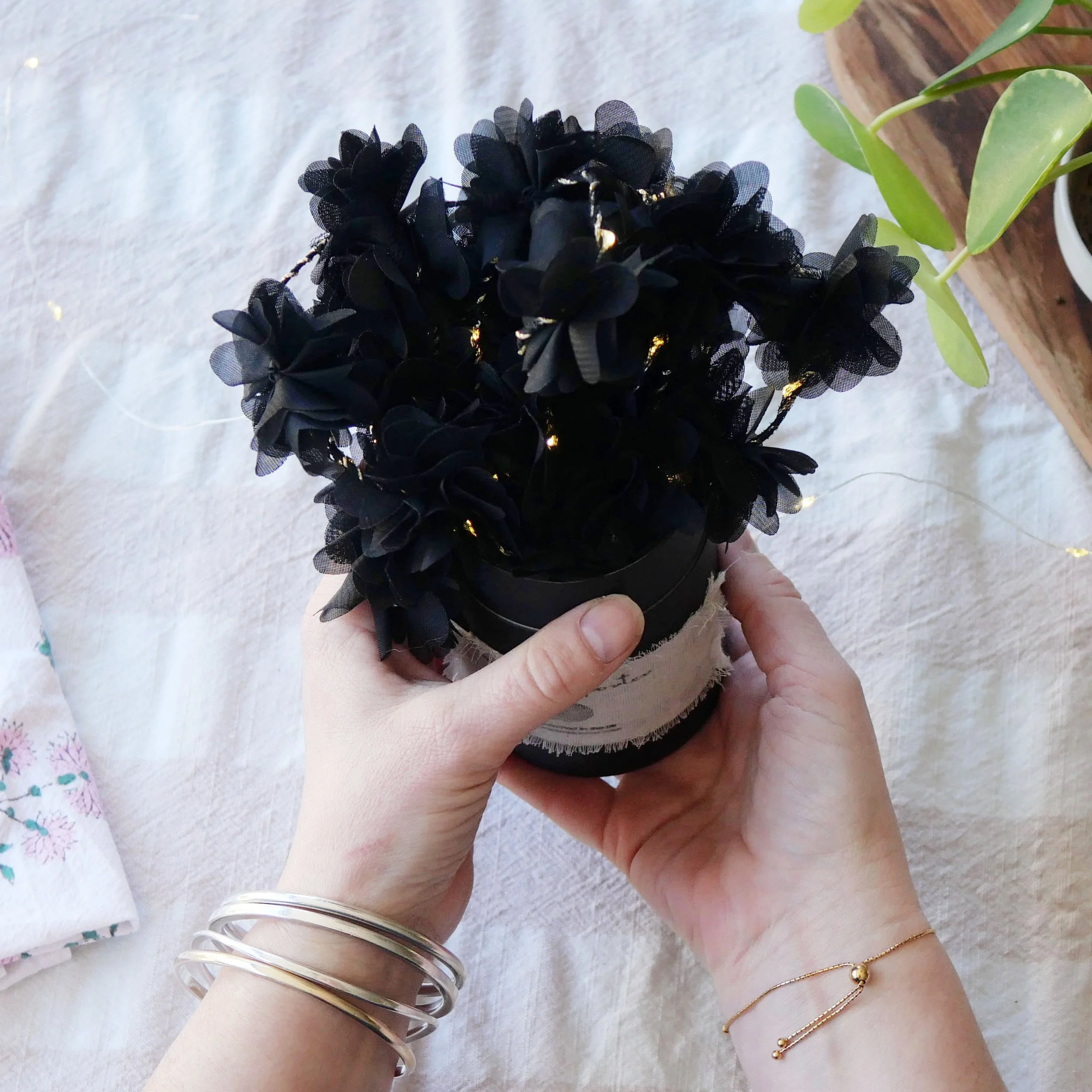 Handmade black chiffon flower fairy lights shown by hand for scale
