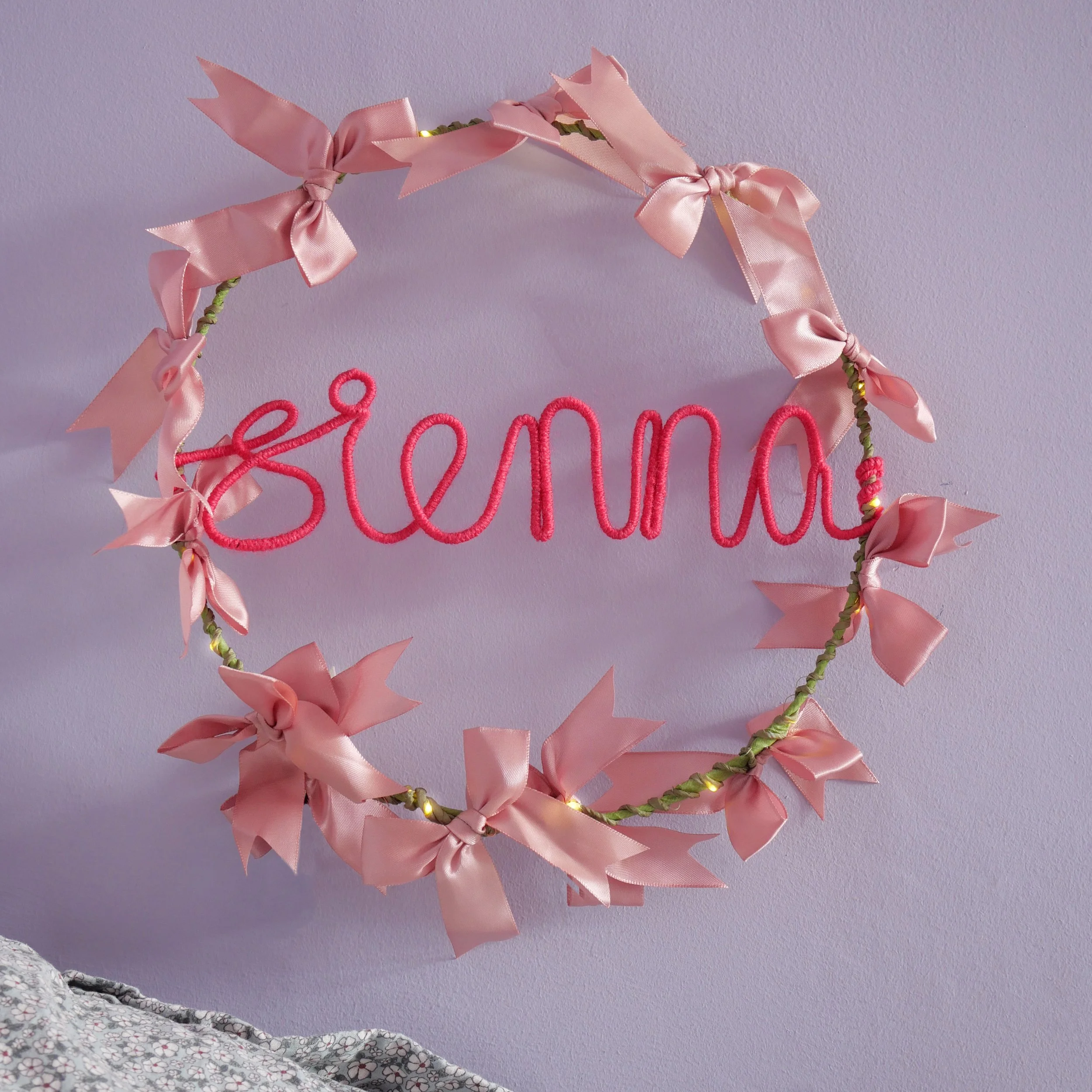 Personalised satin bow hoop light with the name Sienna in neon pink yarn, pink bows and warm white LEDs.