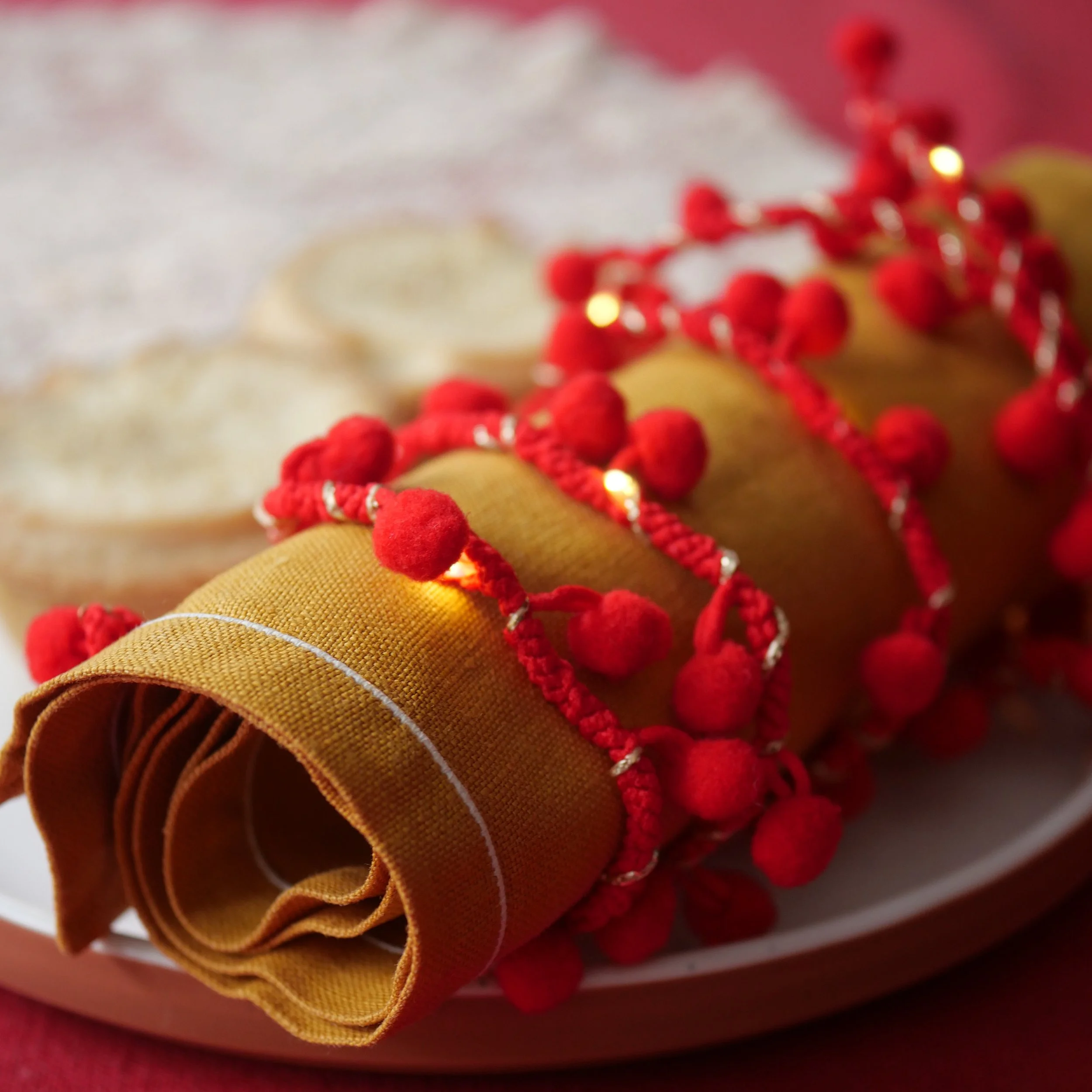 Red pom pom fairy lights styled on a festive dining table