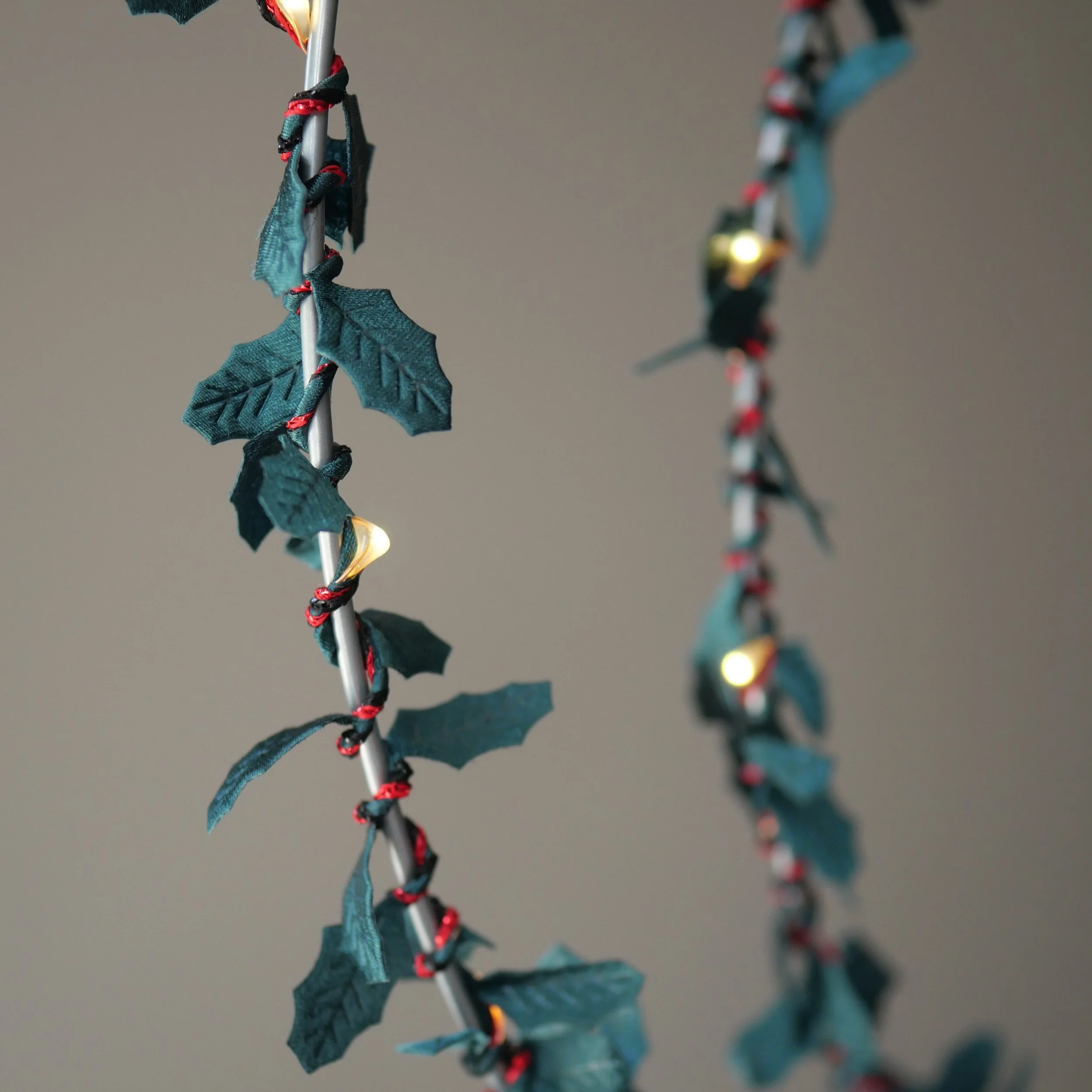 Close-up of handmade green holly fairy lights with red detailing and warm white LEDs.