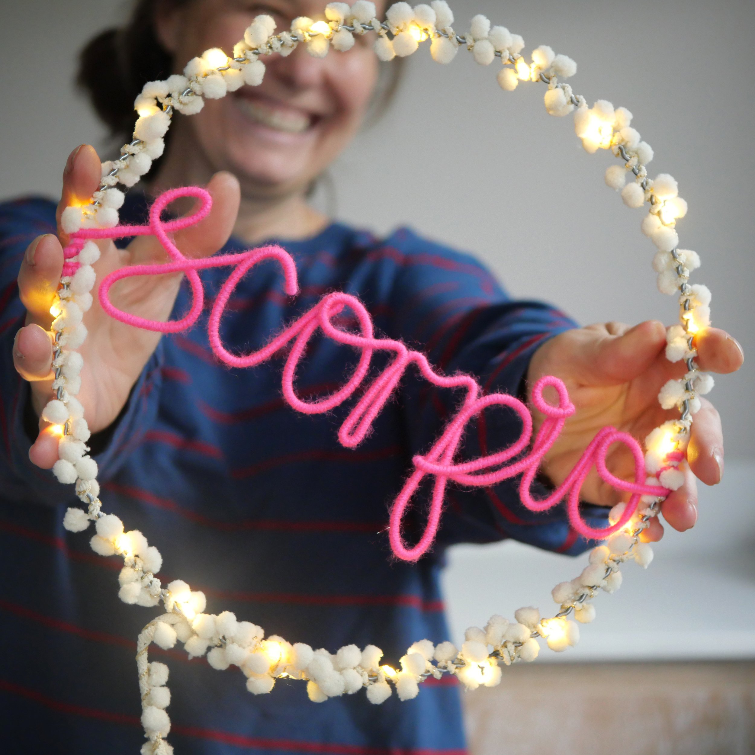 White pom pom personalised message hoop light with pink Scorpio star sign lettering and warm white LEDs