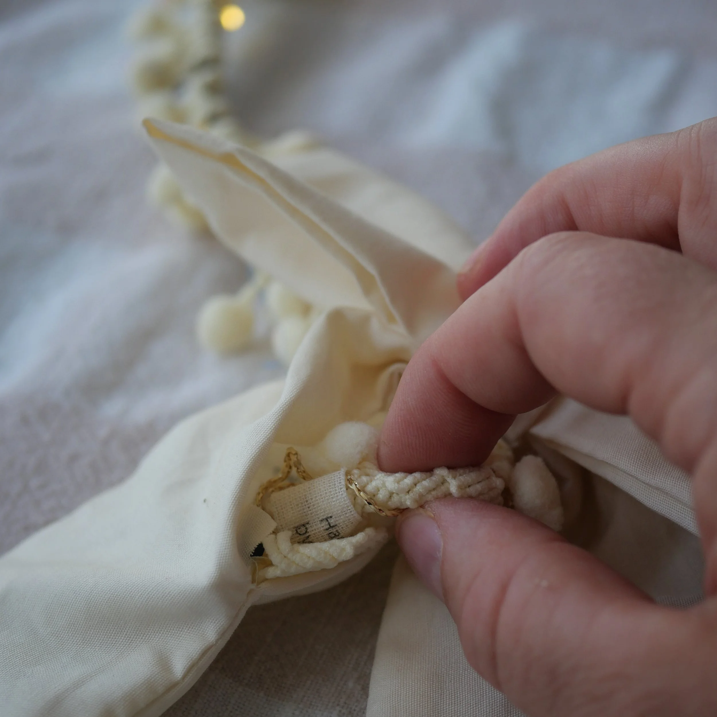 Fairy light battery pack being tucked inside a cream fabric bow cover