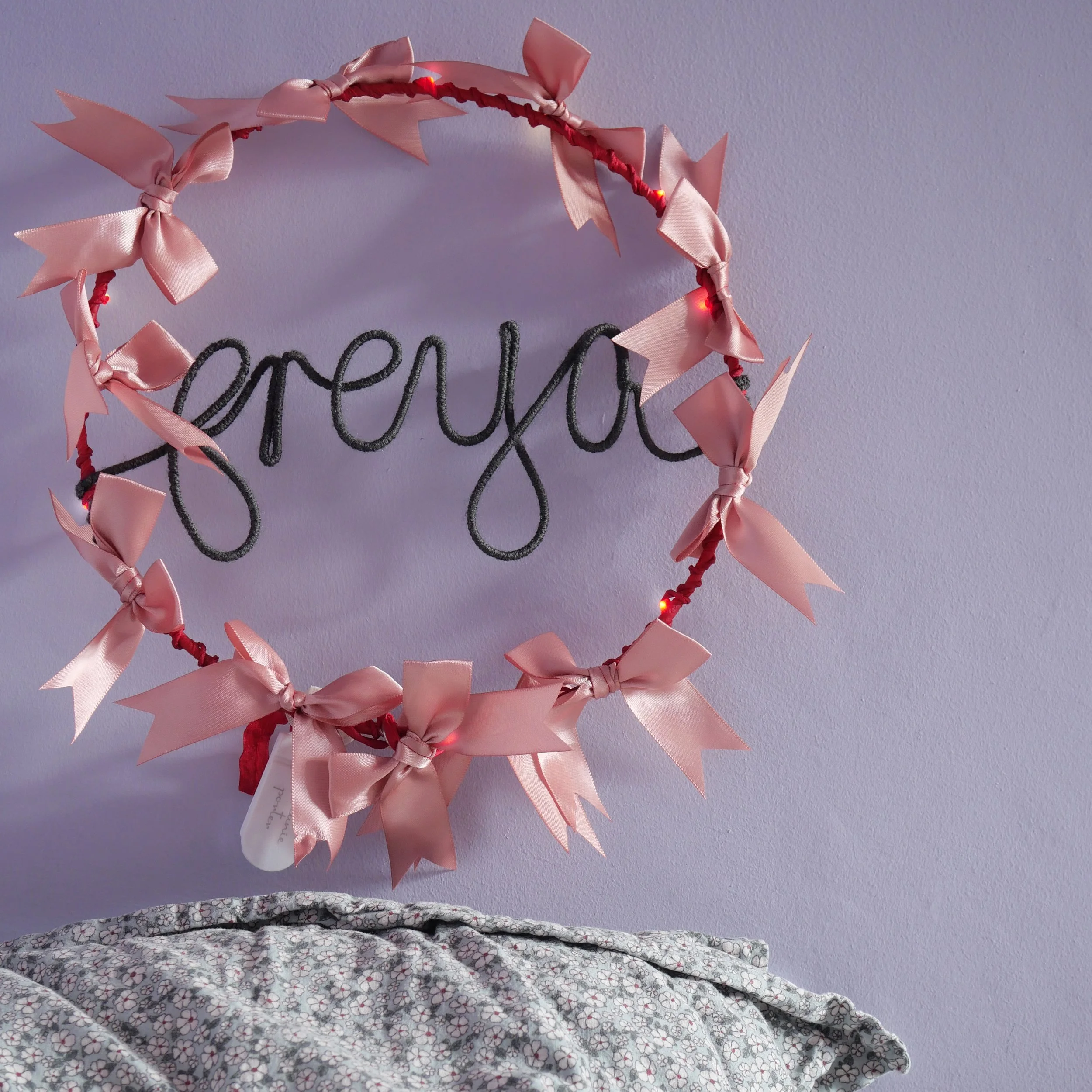 4  Personalised satin bow hoop light with pink bows, red frame and Freya written in warm grey yarn.
