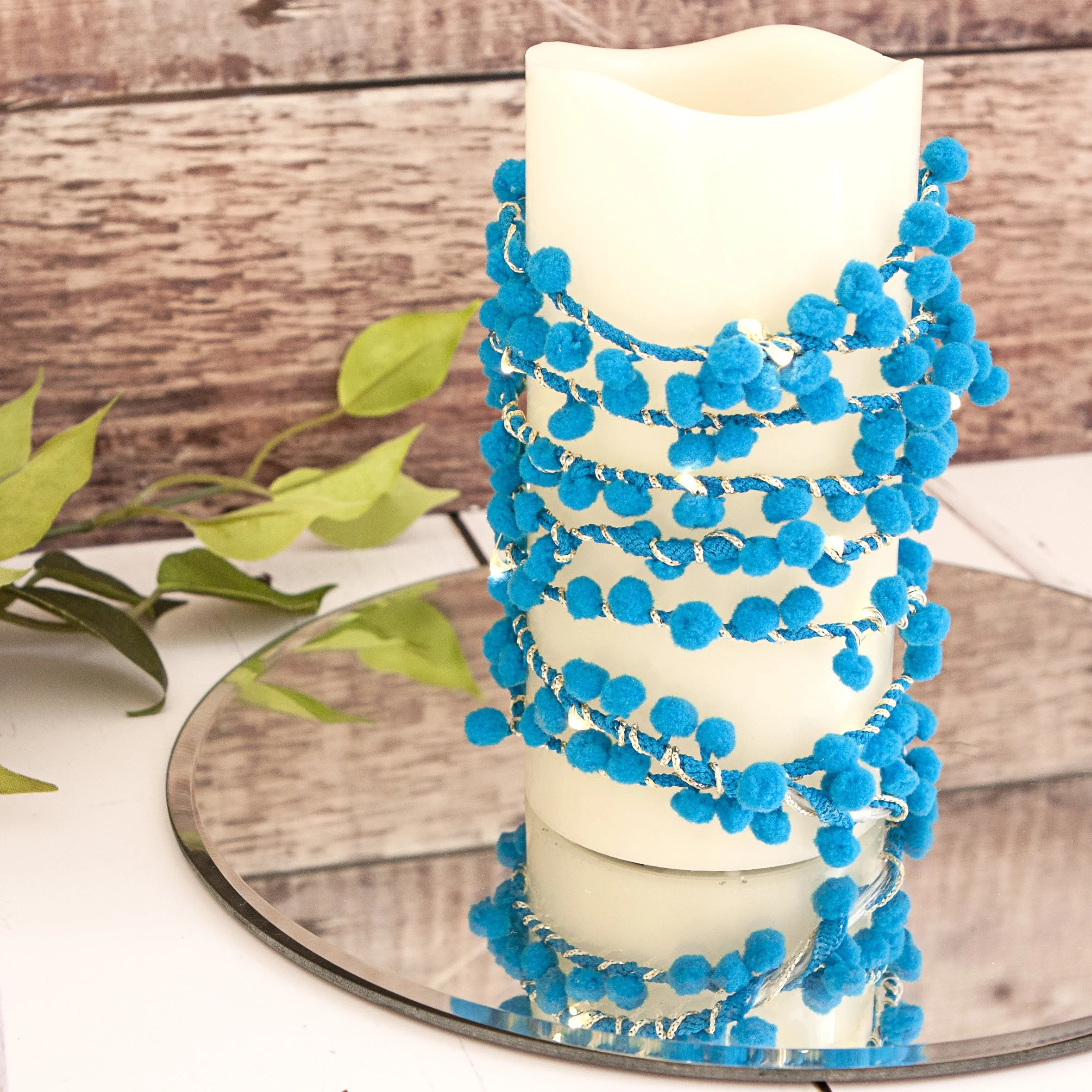 Cobalt blue pom pom fairy lights styled around a glowing candle