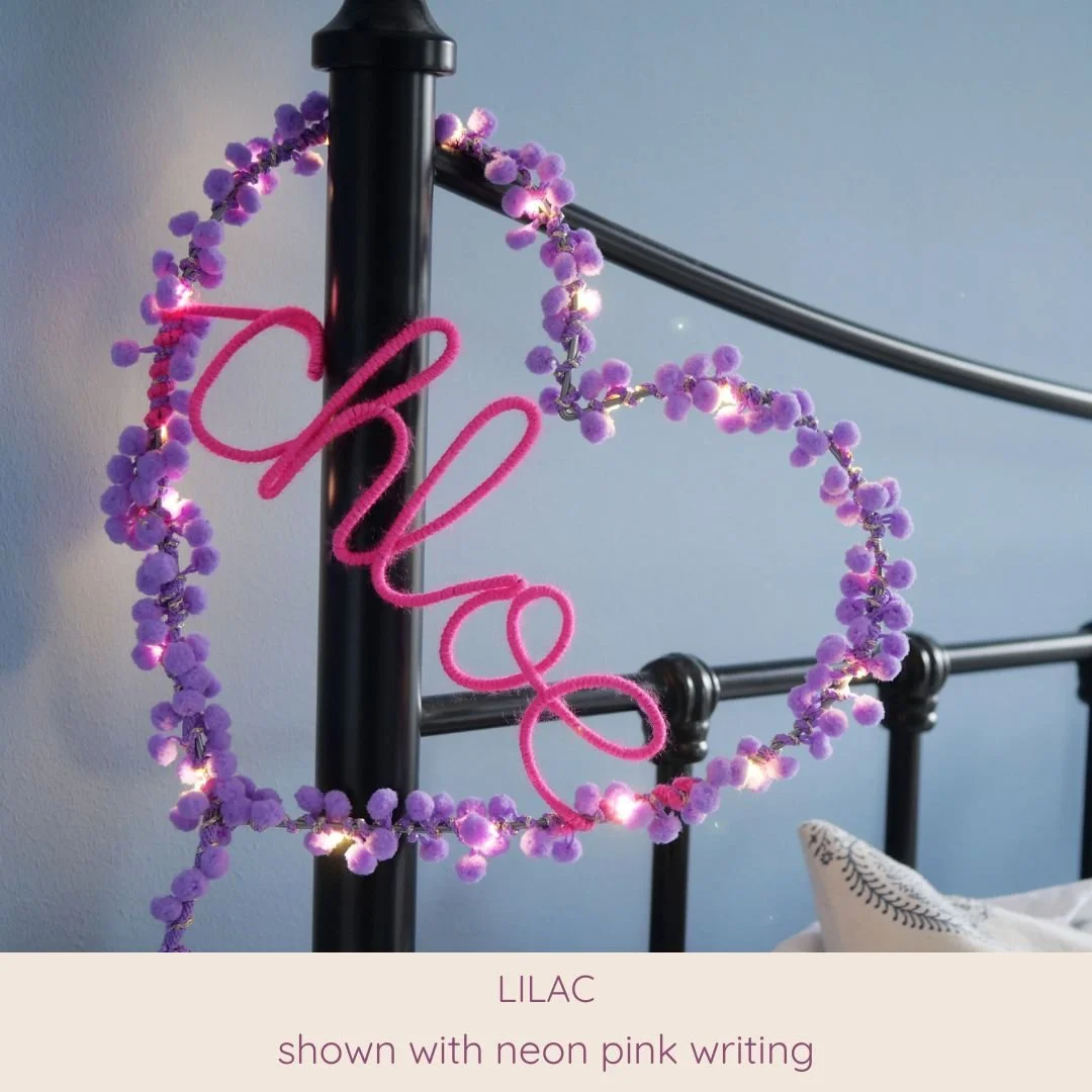 Lilac personalised heart light with Chloe name in neon pink displayed in a bedroom