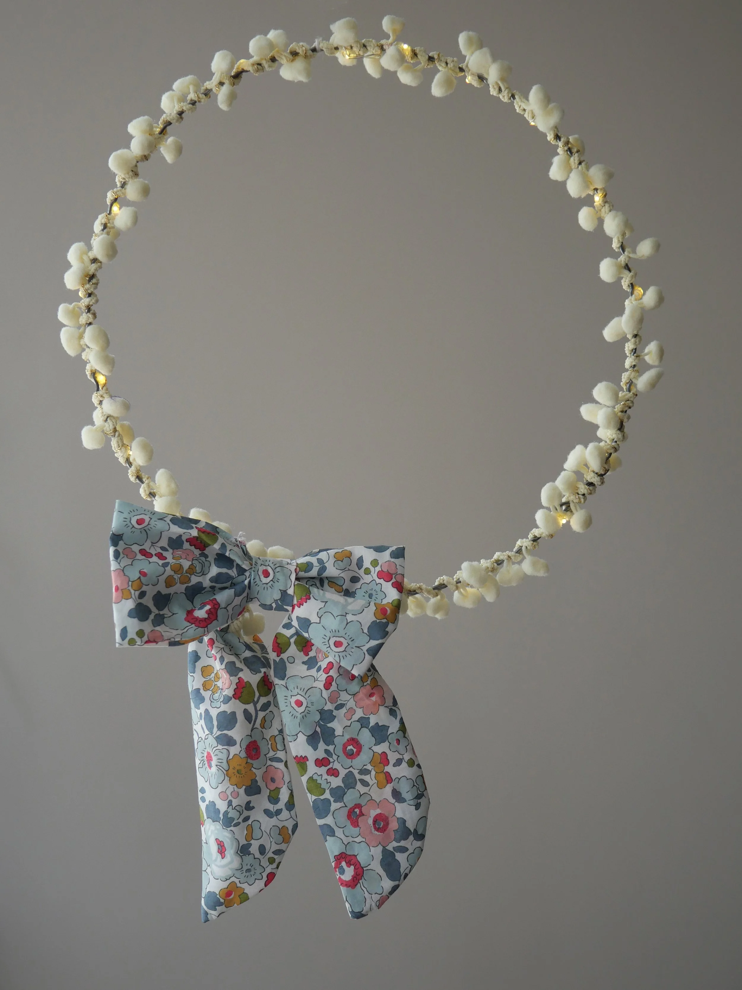 Liberty floral battery cover bow displayed on pom pom fairy lights
