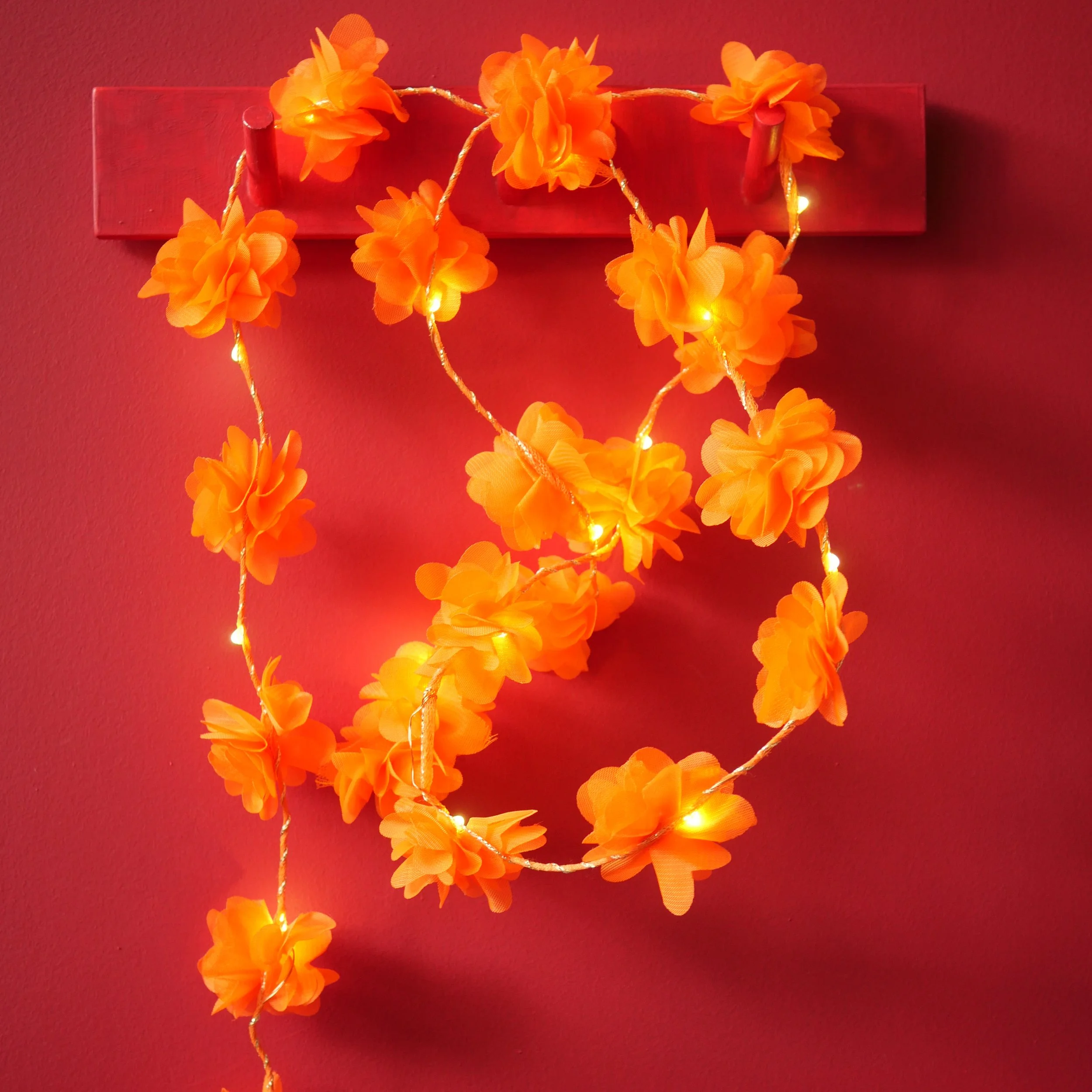 Orange flower fairy lights glowing against a rich red background for Diwali and celebration decorating