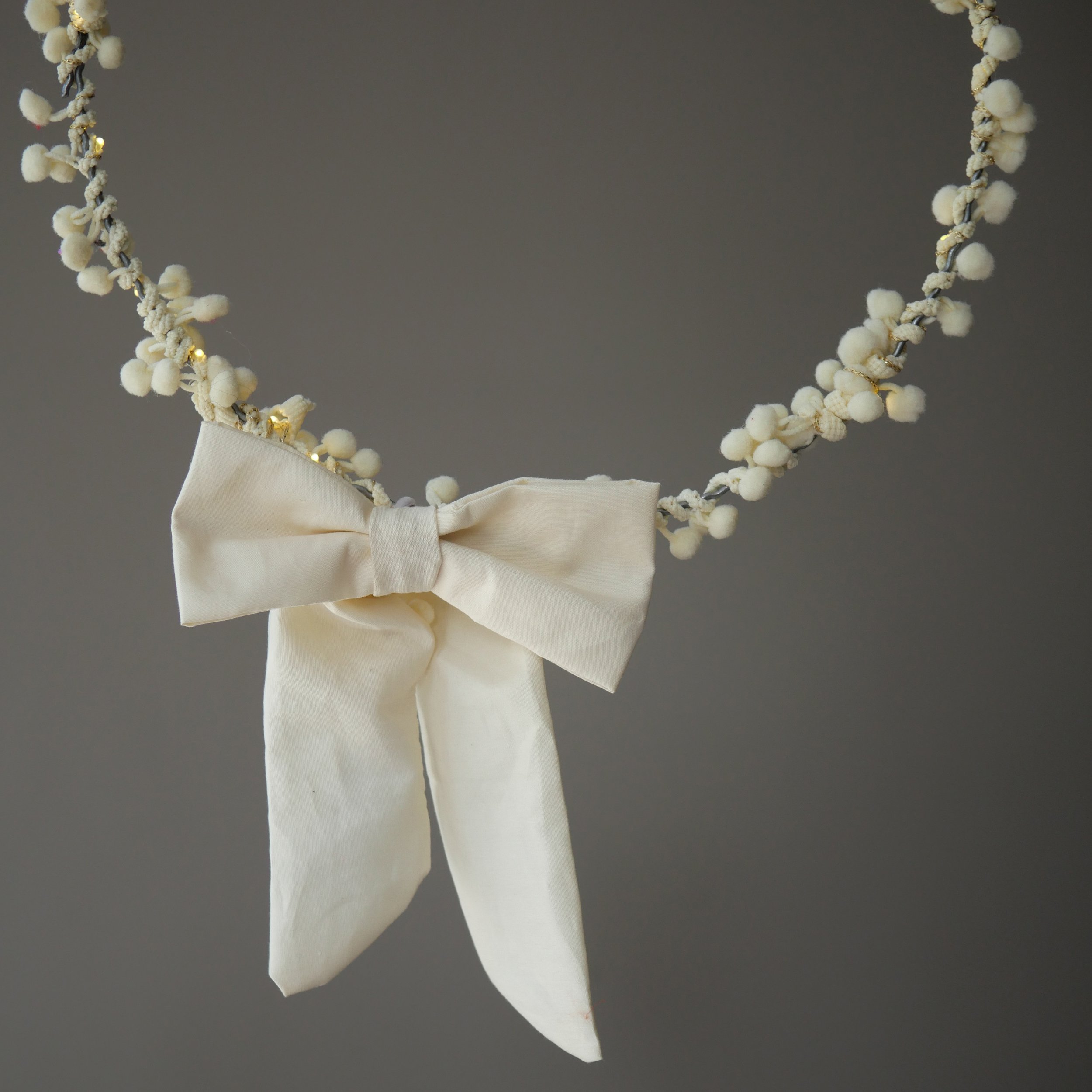 Cream fabric bow hiding the battery pack on pom pom fairy lights
