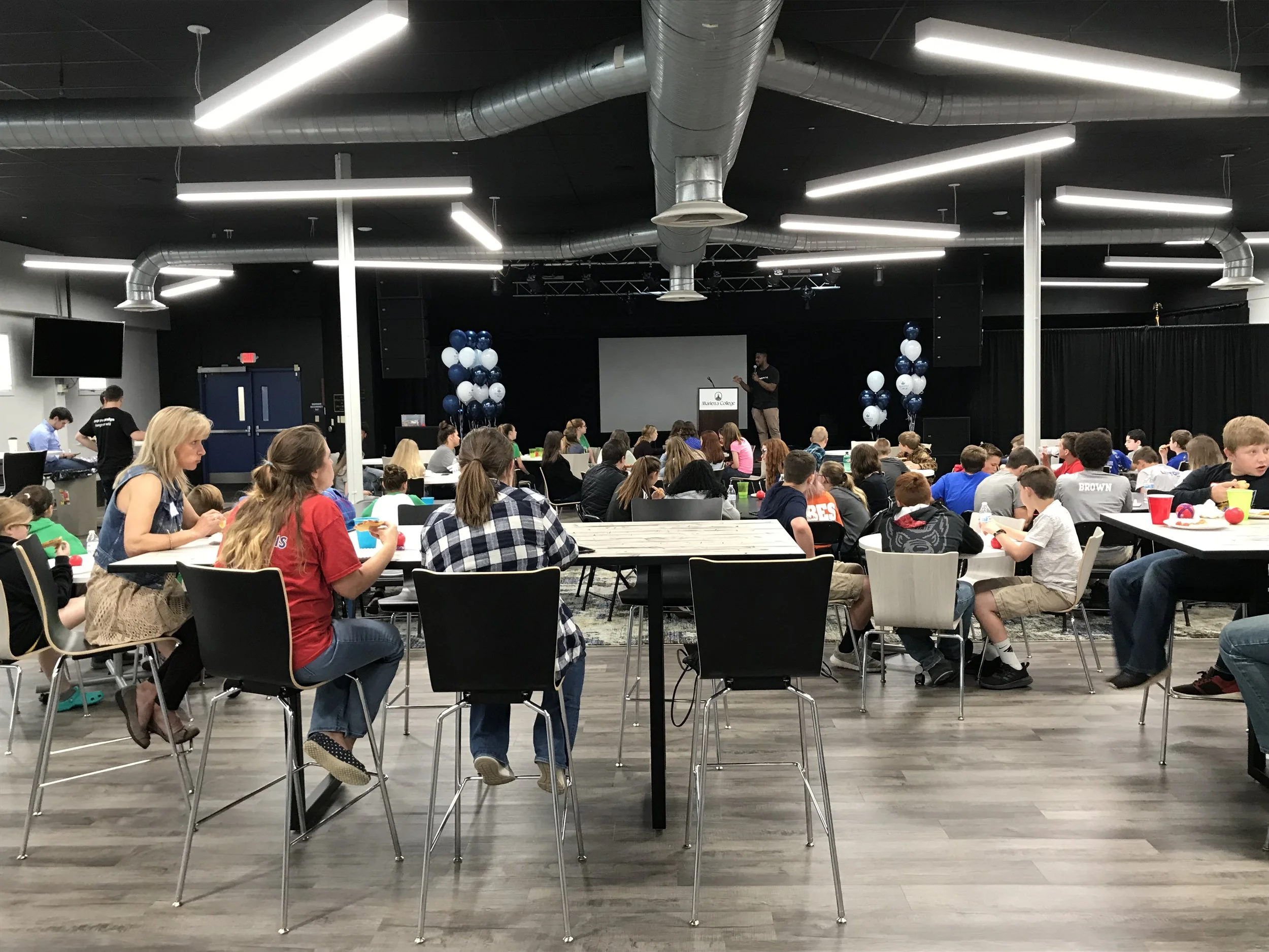Over 100 students enjoy a presentation during their lunch.