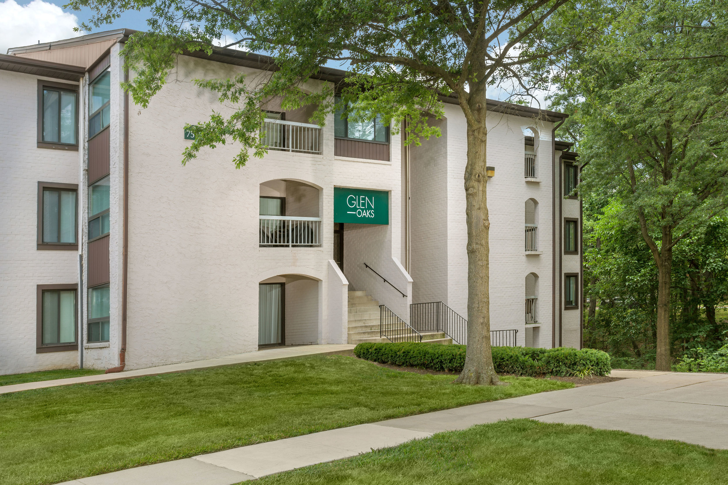 Exterior building view of Glen Oaks apartments with trees and grass all around