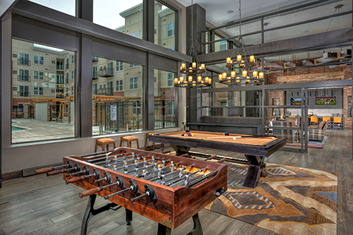 Resident game room at The Remy apartments with foosball and pool tables