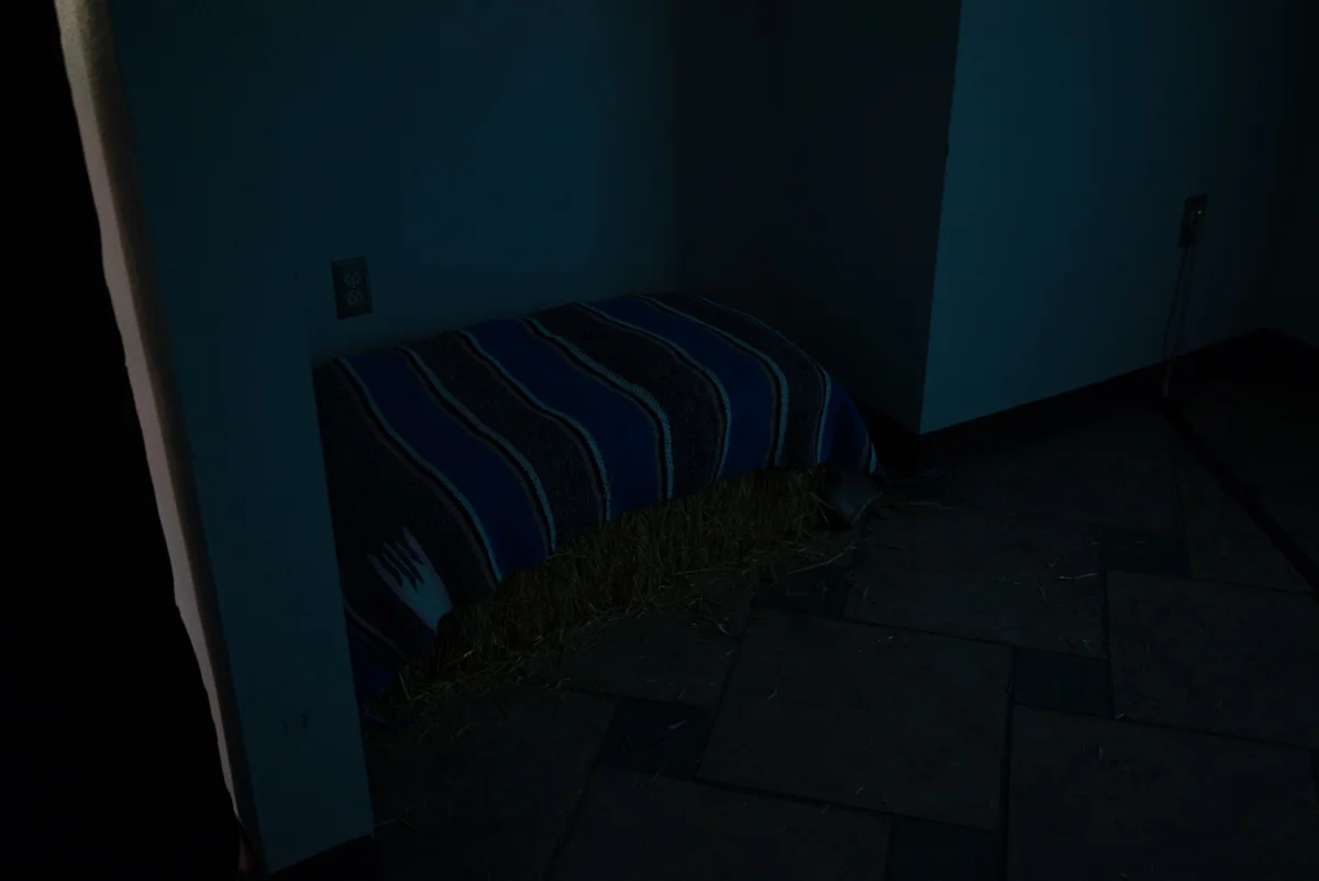 Installation view of straw bale for viewing small room with three-channel video piece Country Songs