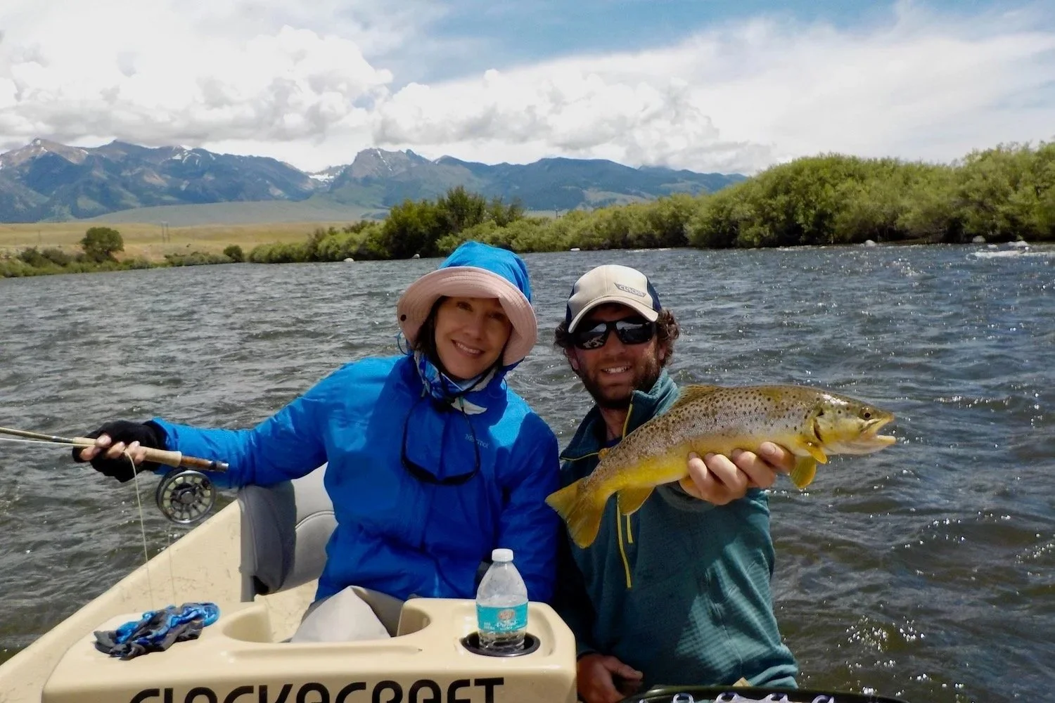 A smiling lady angler and guide David Kern with a large brown trout caught while float fishing the Madison River near Ennis, MT.
