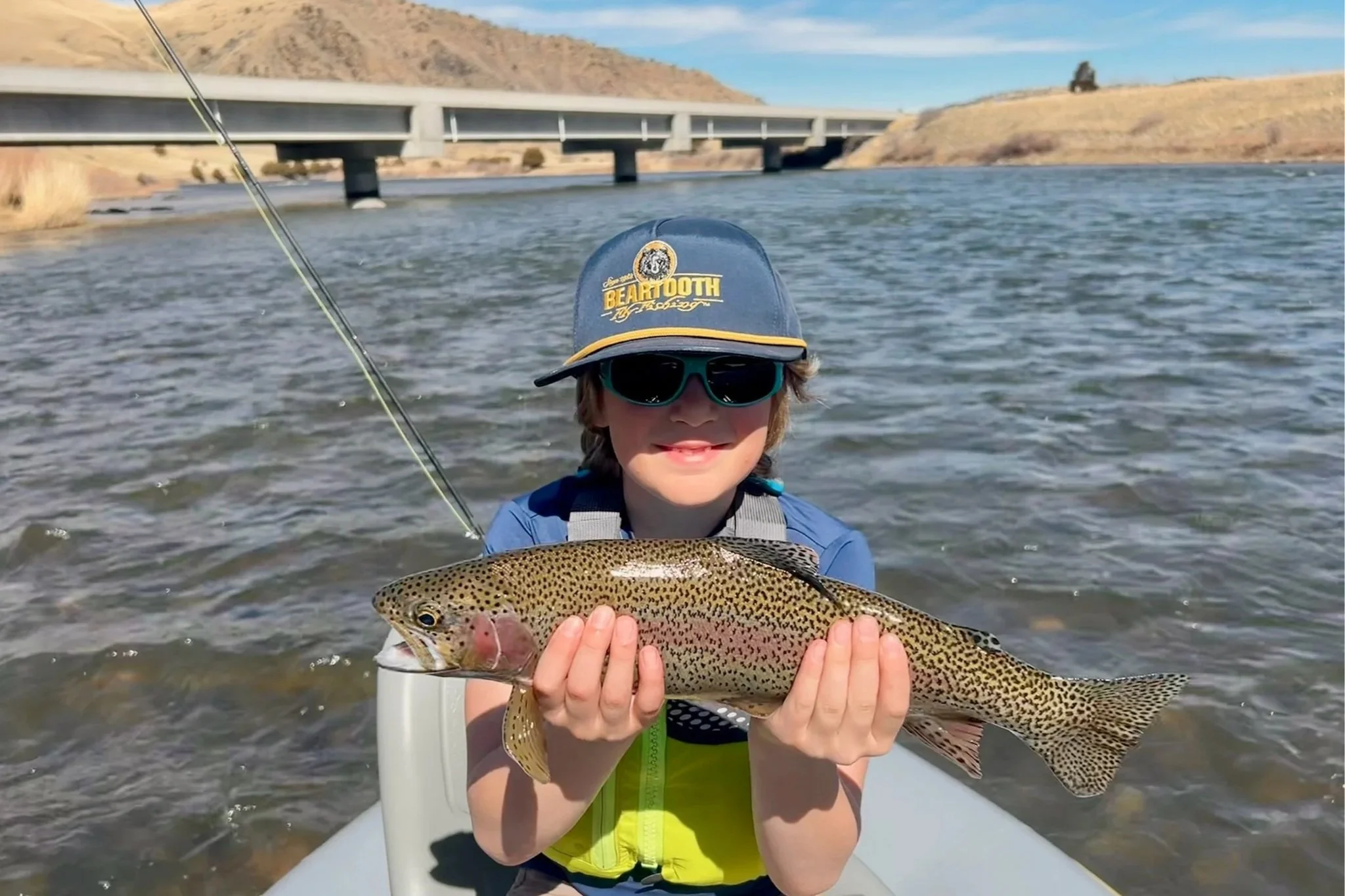 A happy family enjoying a guided fly fishing trip on the Lower Madison River near Bozeman, capturing the relaxed and beginner-friendly atmosphere that Flyshot Outfitters provides for all ages.