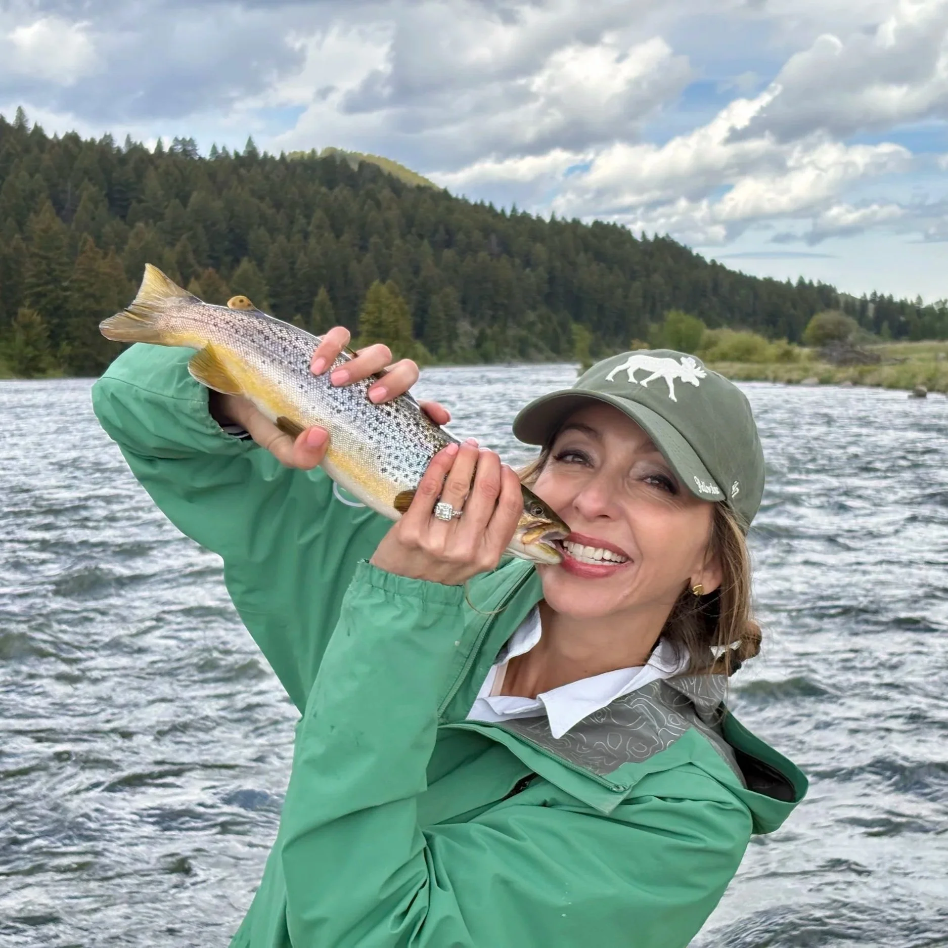 An angler kissing a large brown trout caught streamer fishing on the Upper Madison River.