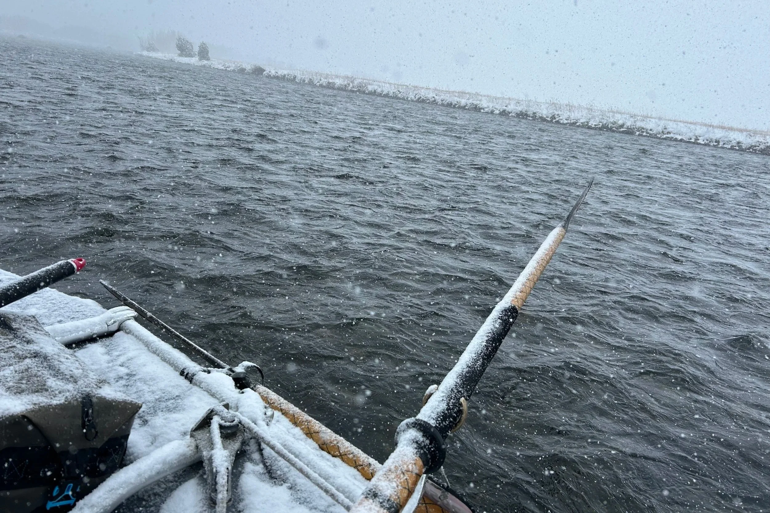 A wild April morning on the Madison River during a spring fishing report trip, featuring an oar caked in fresh spring snow as a storm rolls through the valley.