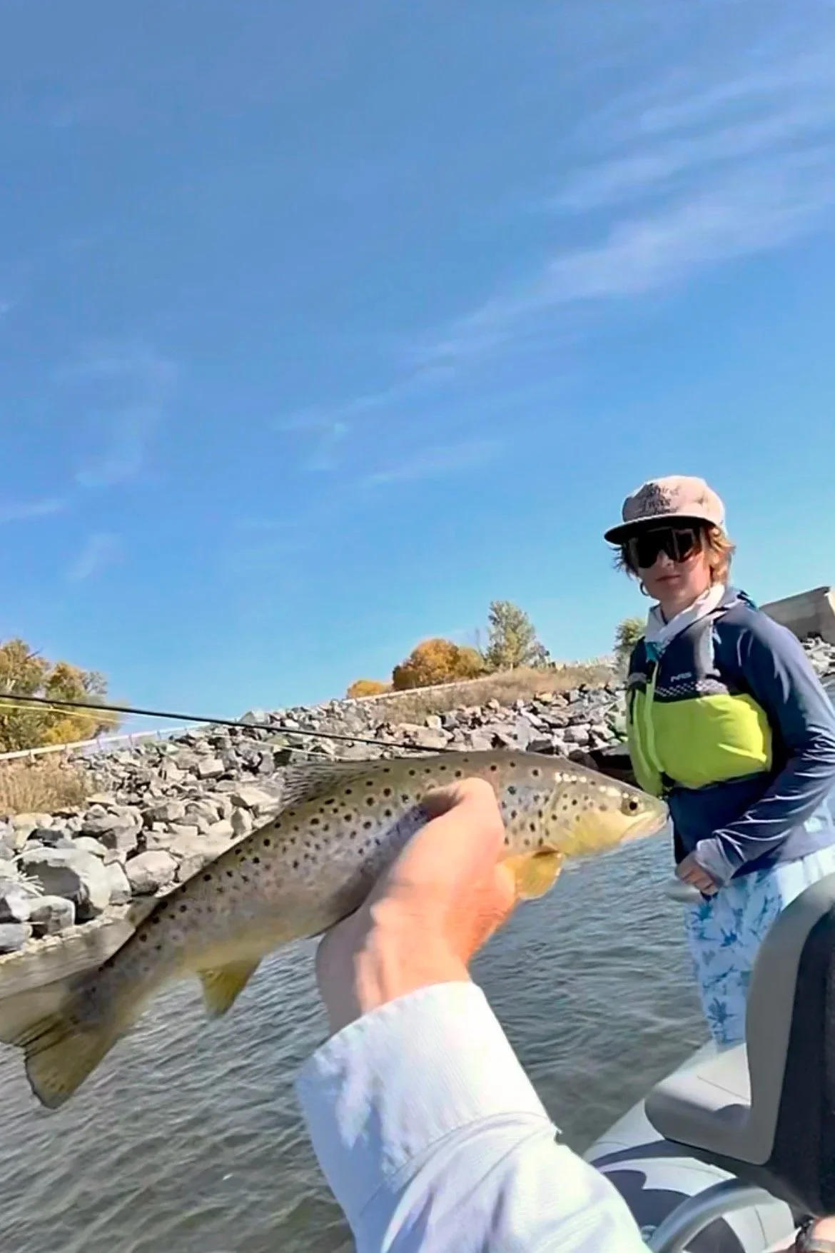 An 11-year-old angler in DarkSeas apparel looks on as a guide safely holds up a wild brown trout just brought to the net on the Yellowstone River.