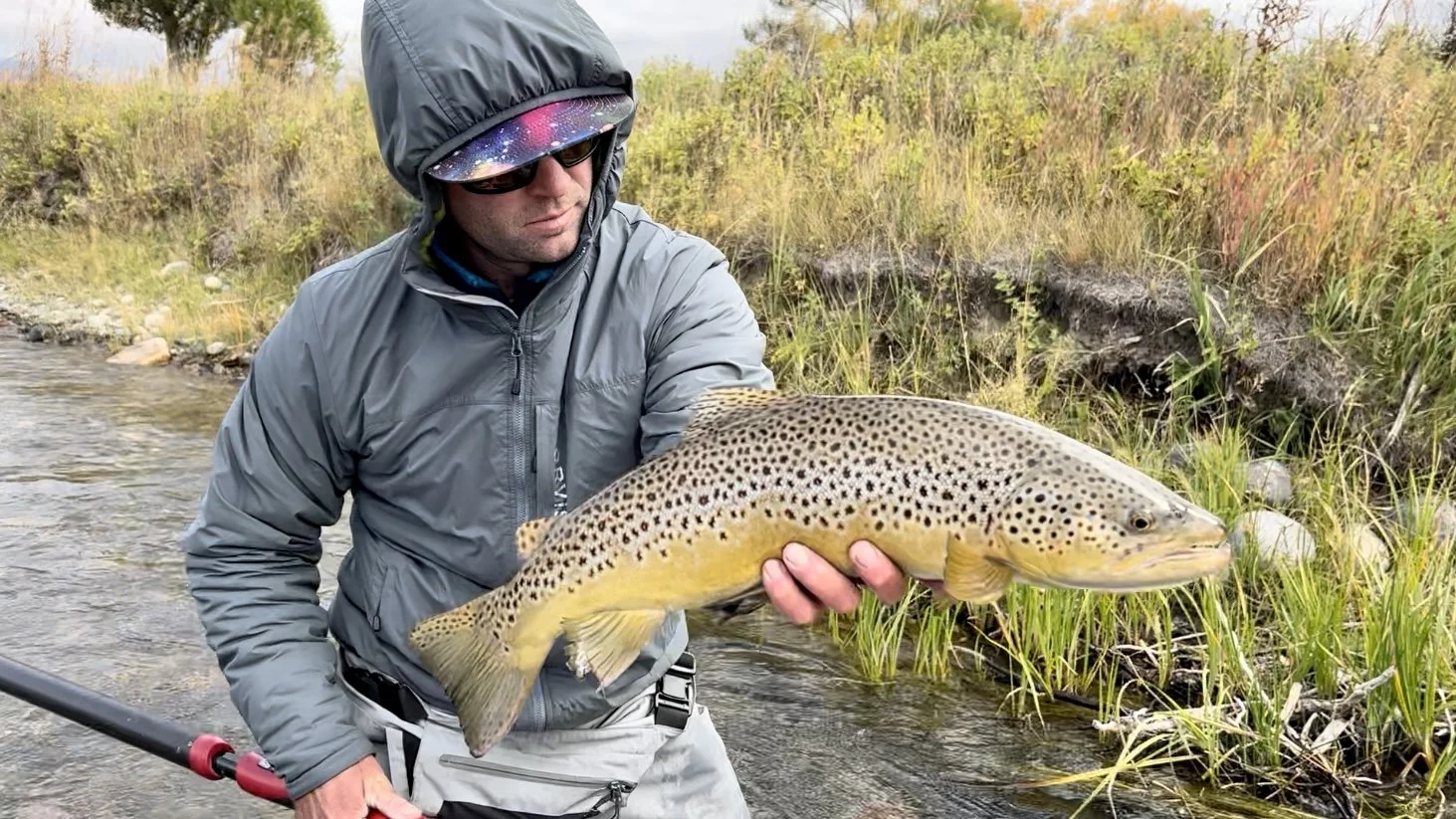 Flyshot Outfitters owner David Kern holding a healthy brown trout along the banks of the Madison River near Bozeman, Montana.