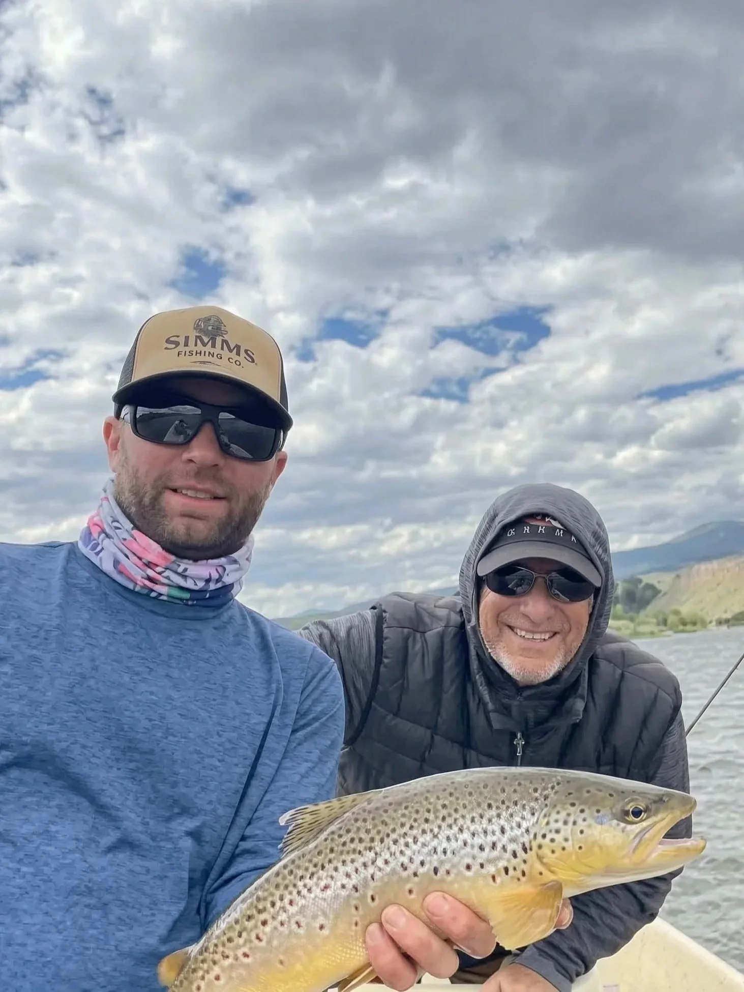A 5-star Google review photo of a smiling client alongside guide David Kern as he holds a Madison River brown trout during a professional drift boat float trip near Bozeman.