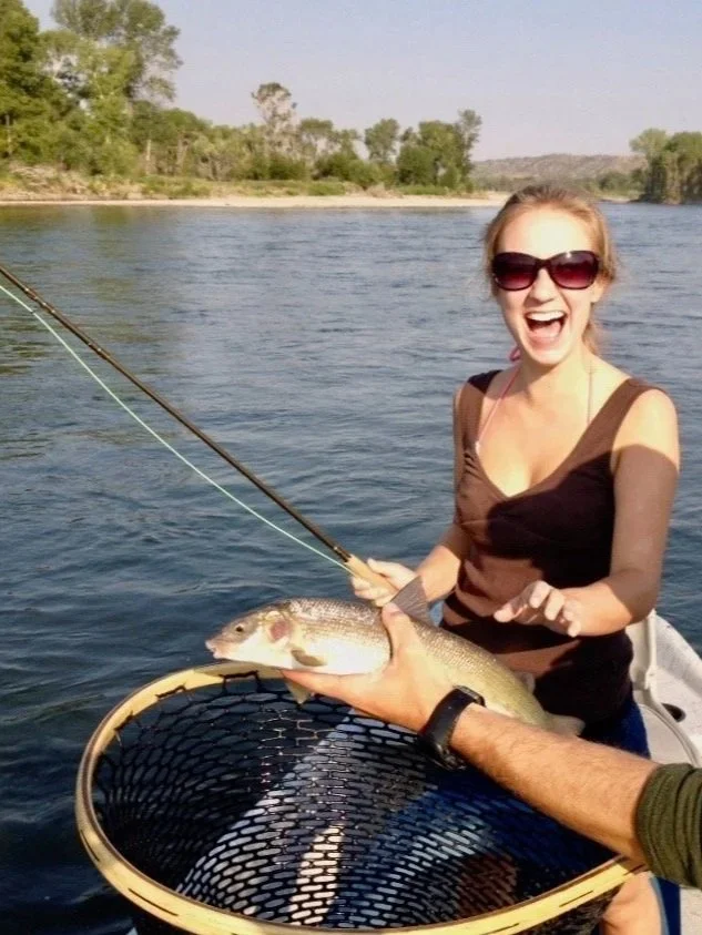 A happy young girl smiling while a Flyshot Outfitters guide holds a native Mountain Whitefish during a family-friendly half-day guided float trip on the Yellowstone River near Livingston.